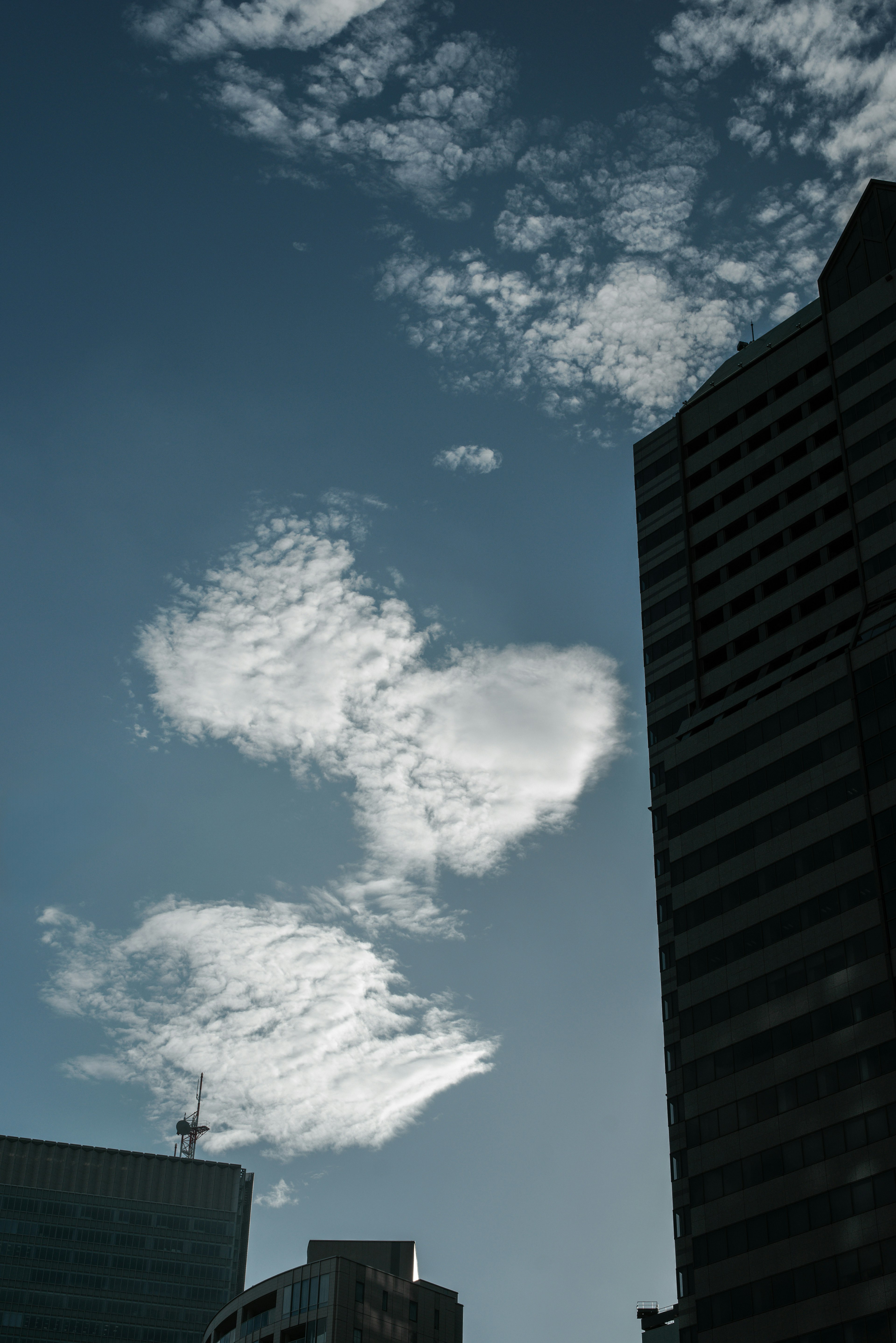 Kontrast zwischen Wolken und blauem Himmel mit Gebäuden im Schatten