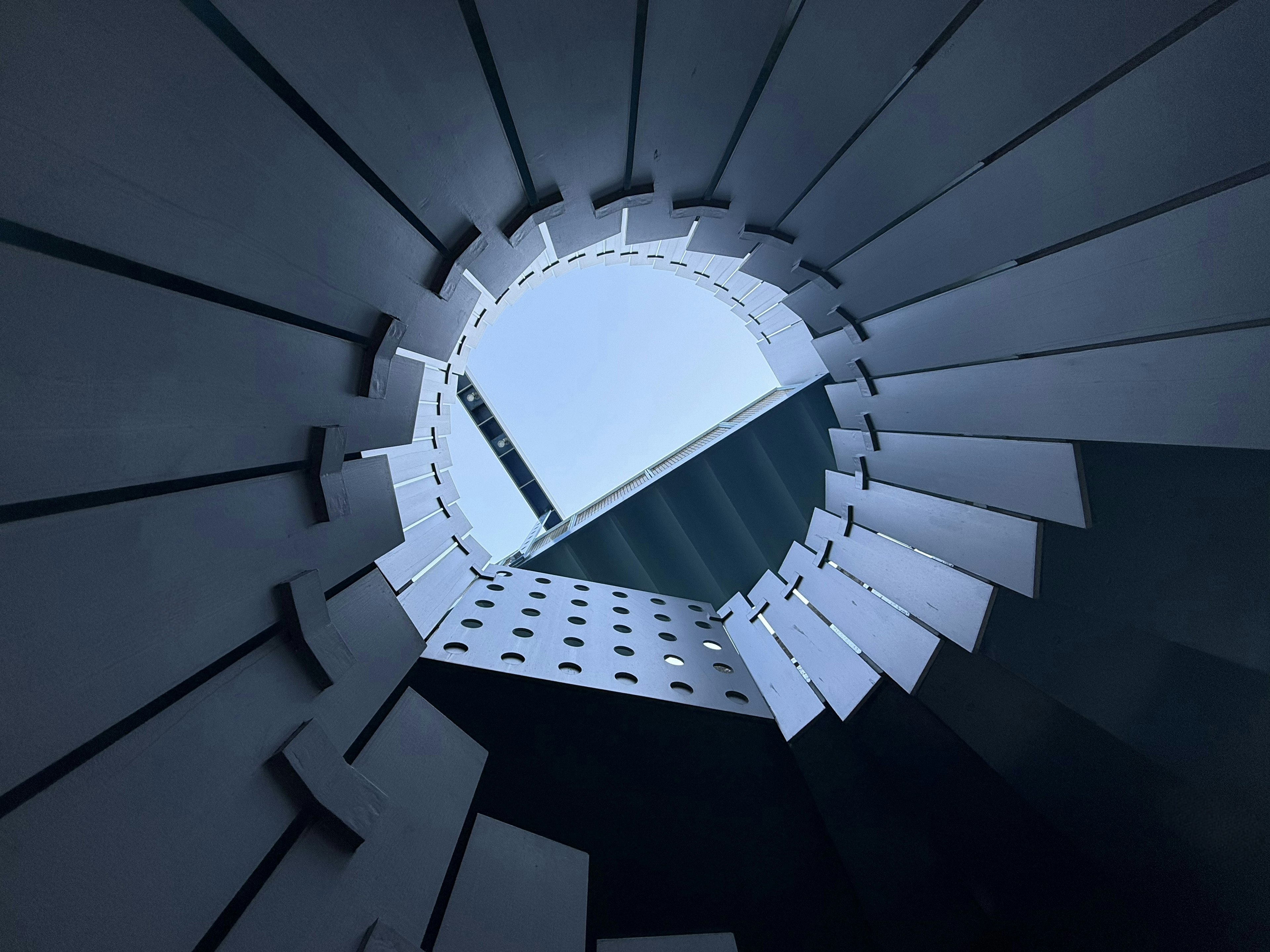 View looking up through a circular architectural structure revealing blue sky