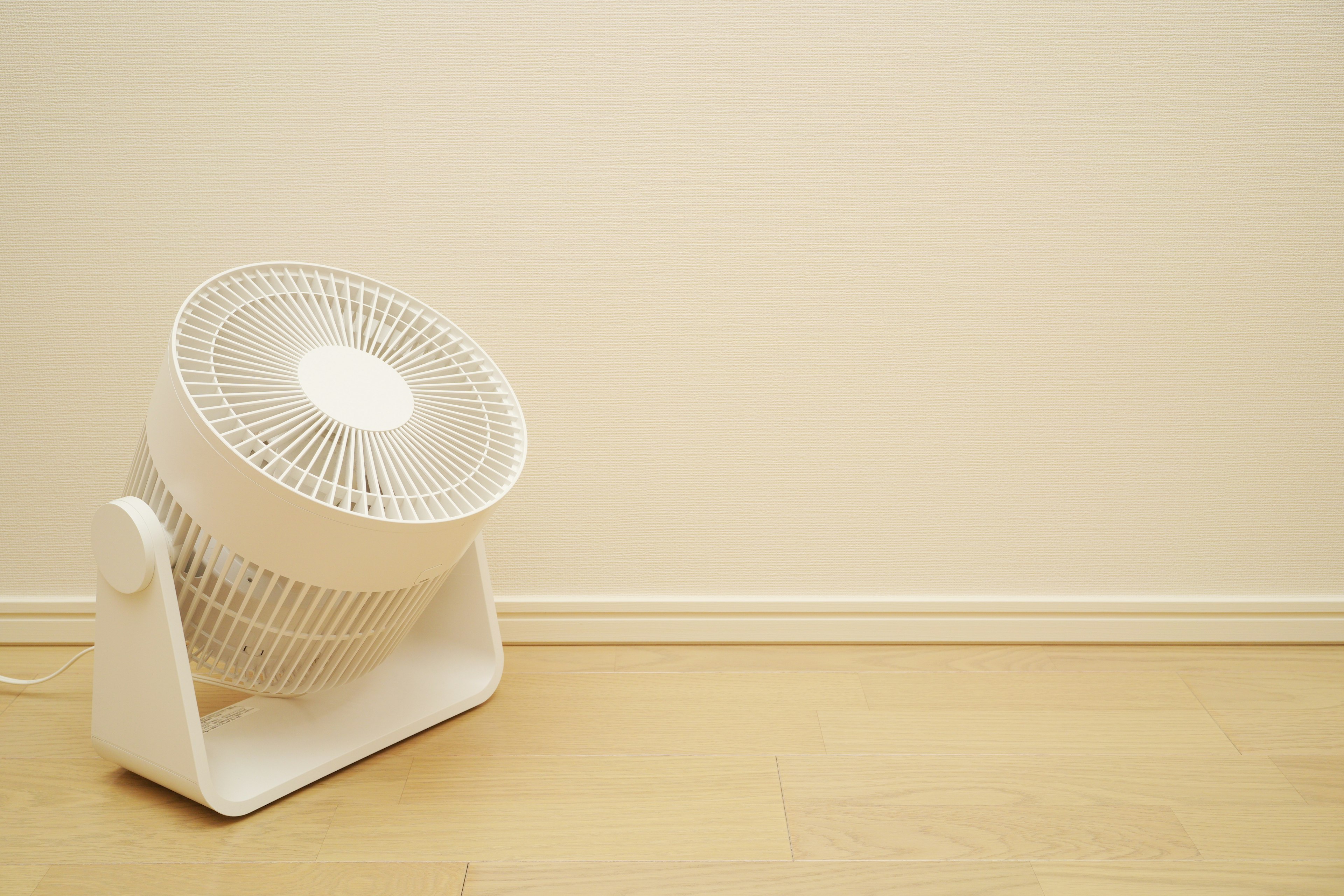 Un ventilateur blanc placé contre un mur dans un coin de pièce simple