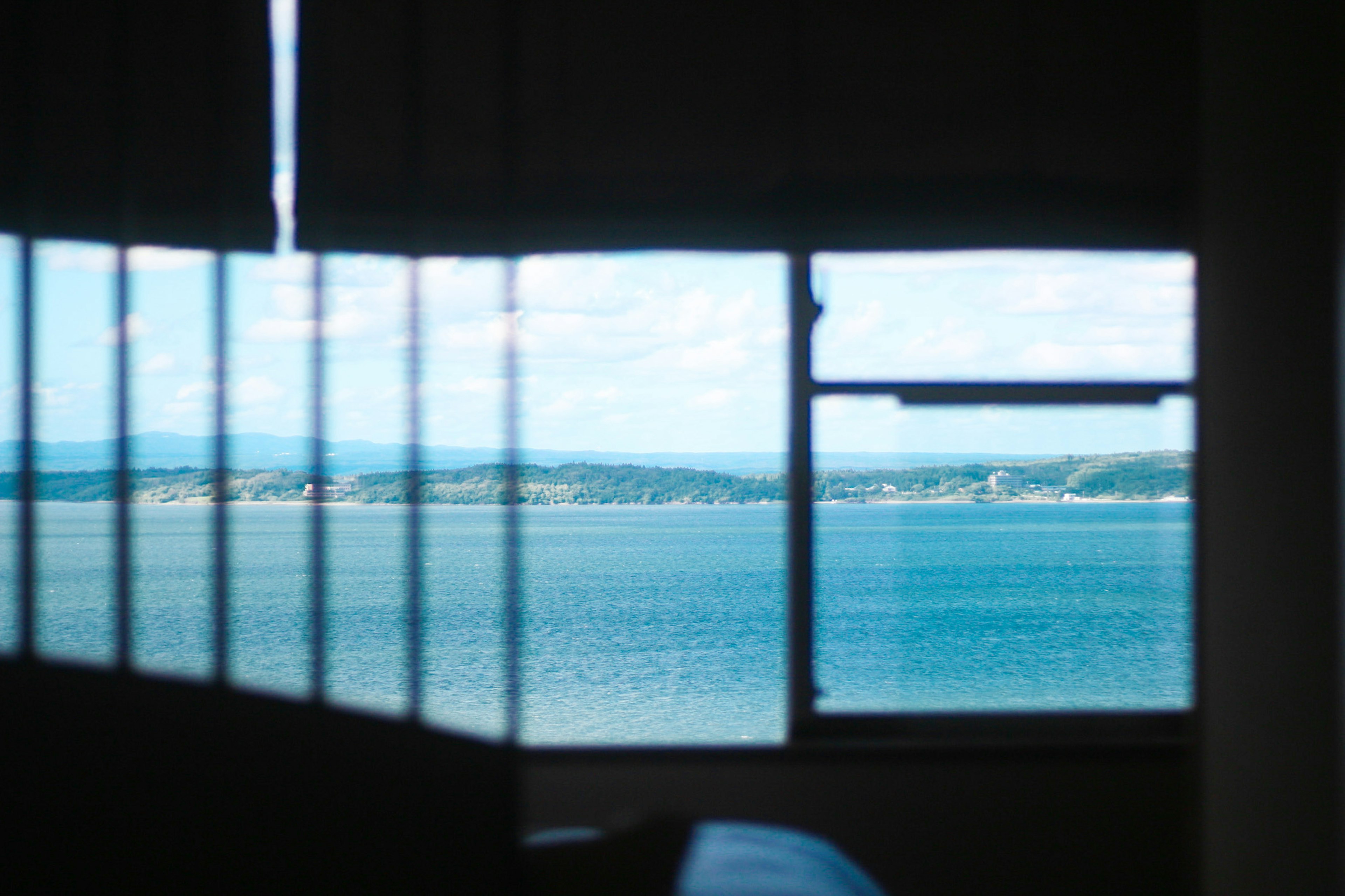 Blick auf das Meer und den blauen Himmel durch ein Fenster