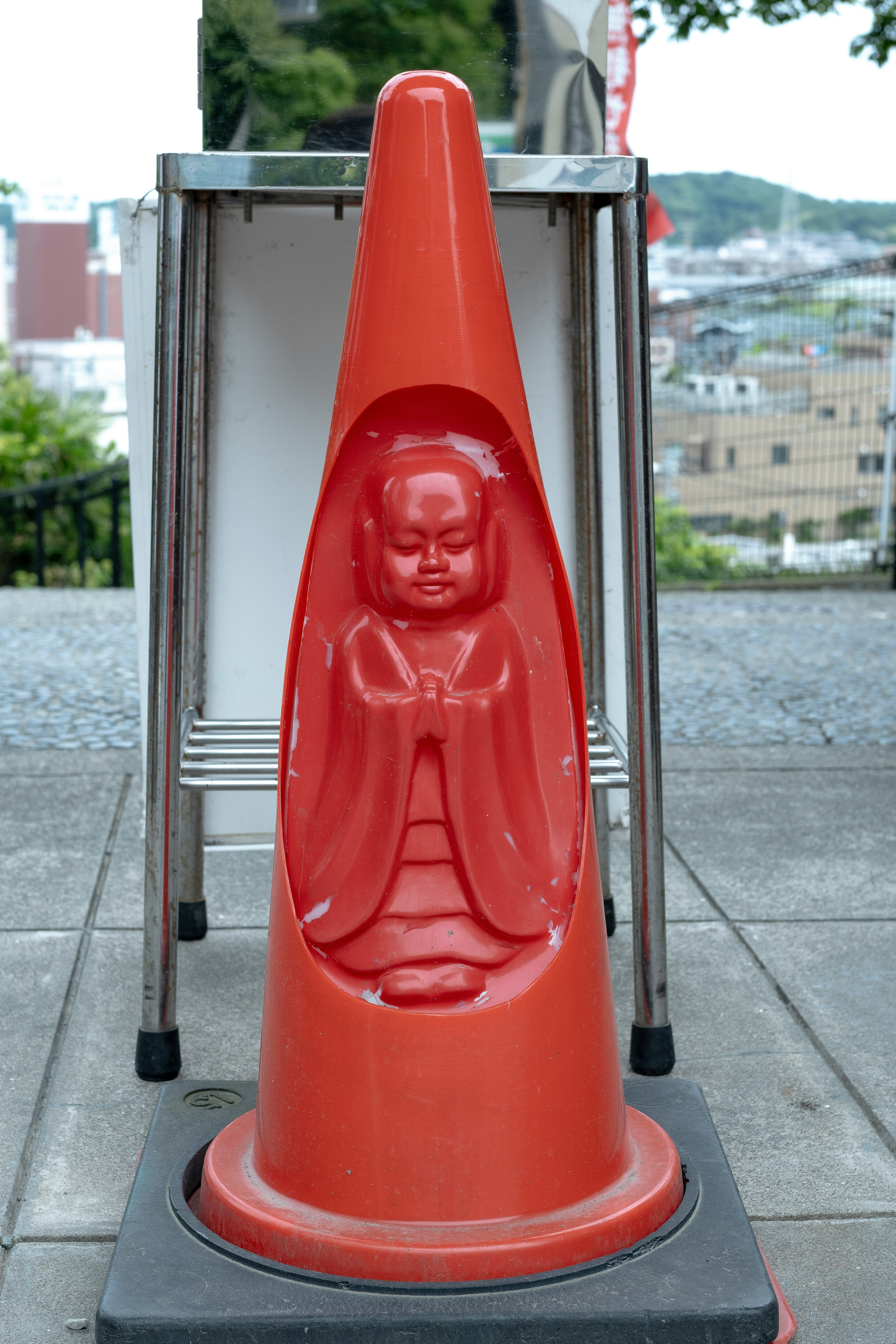 Cono stradale rosso con una statua di Buddha scolpita