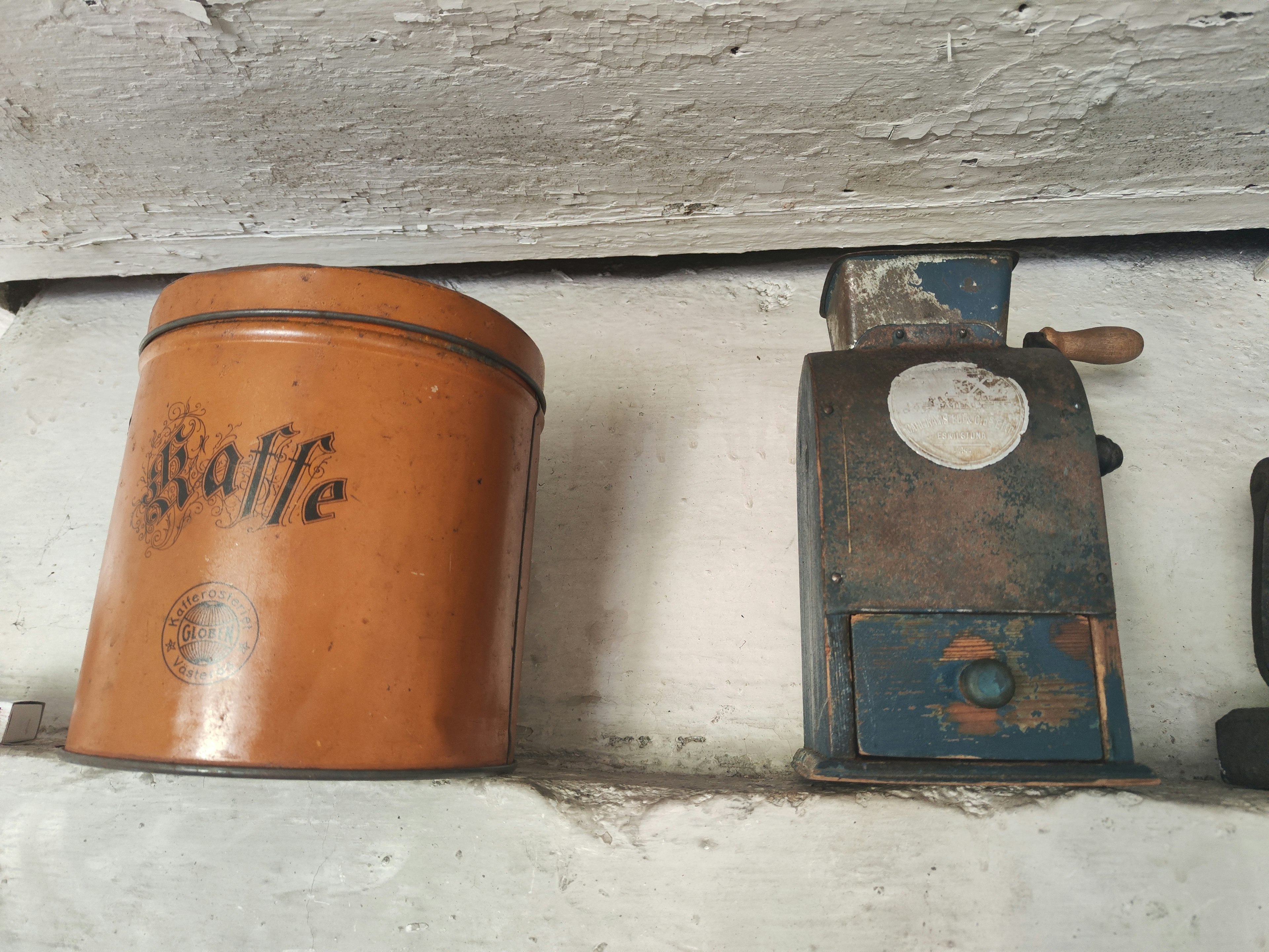 An old coffee can and coffee grinder displayed side by side