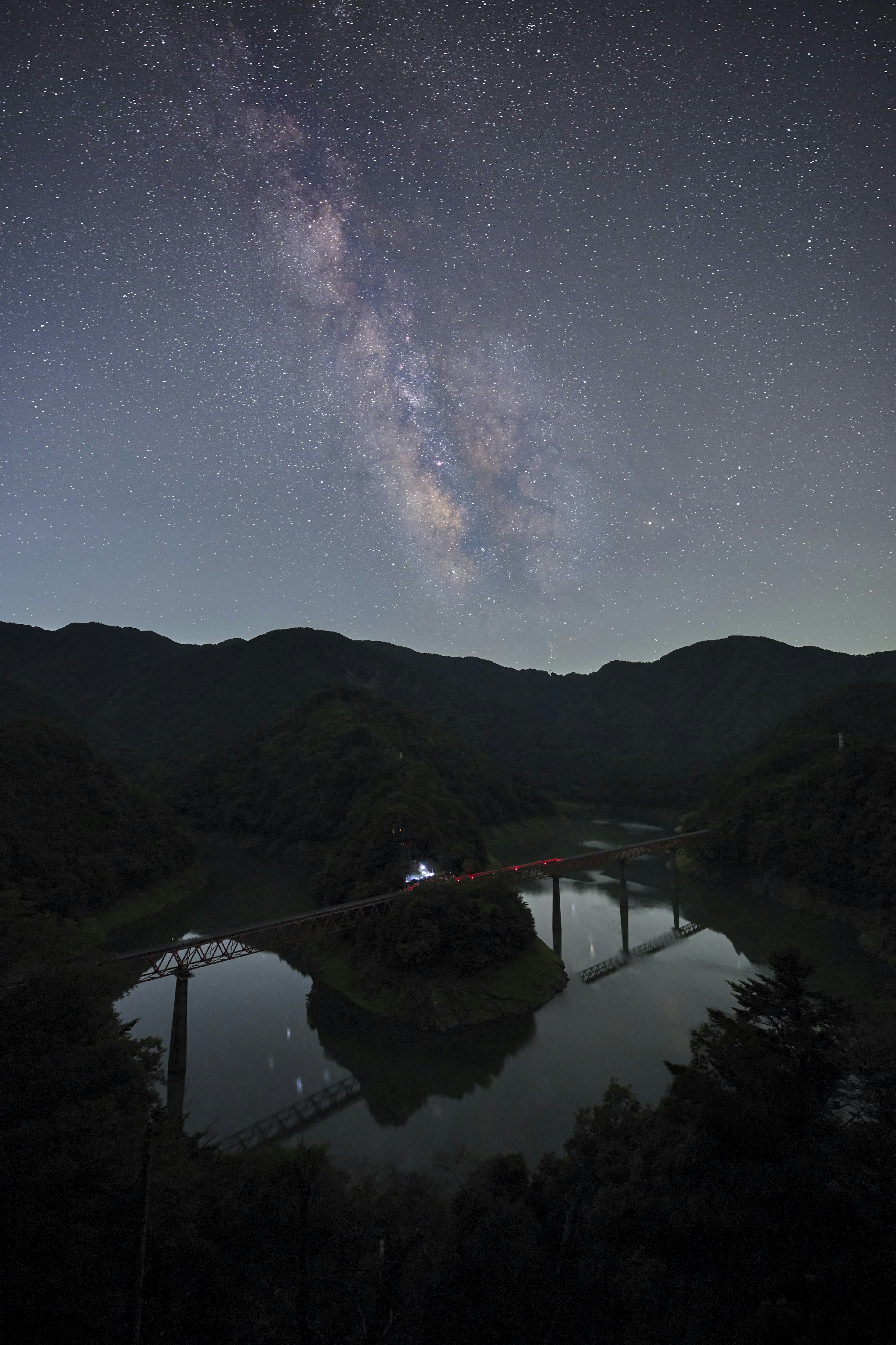 Serene landscape featuring a lake reflecting the Milky Way and mountains