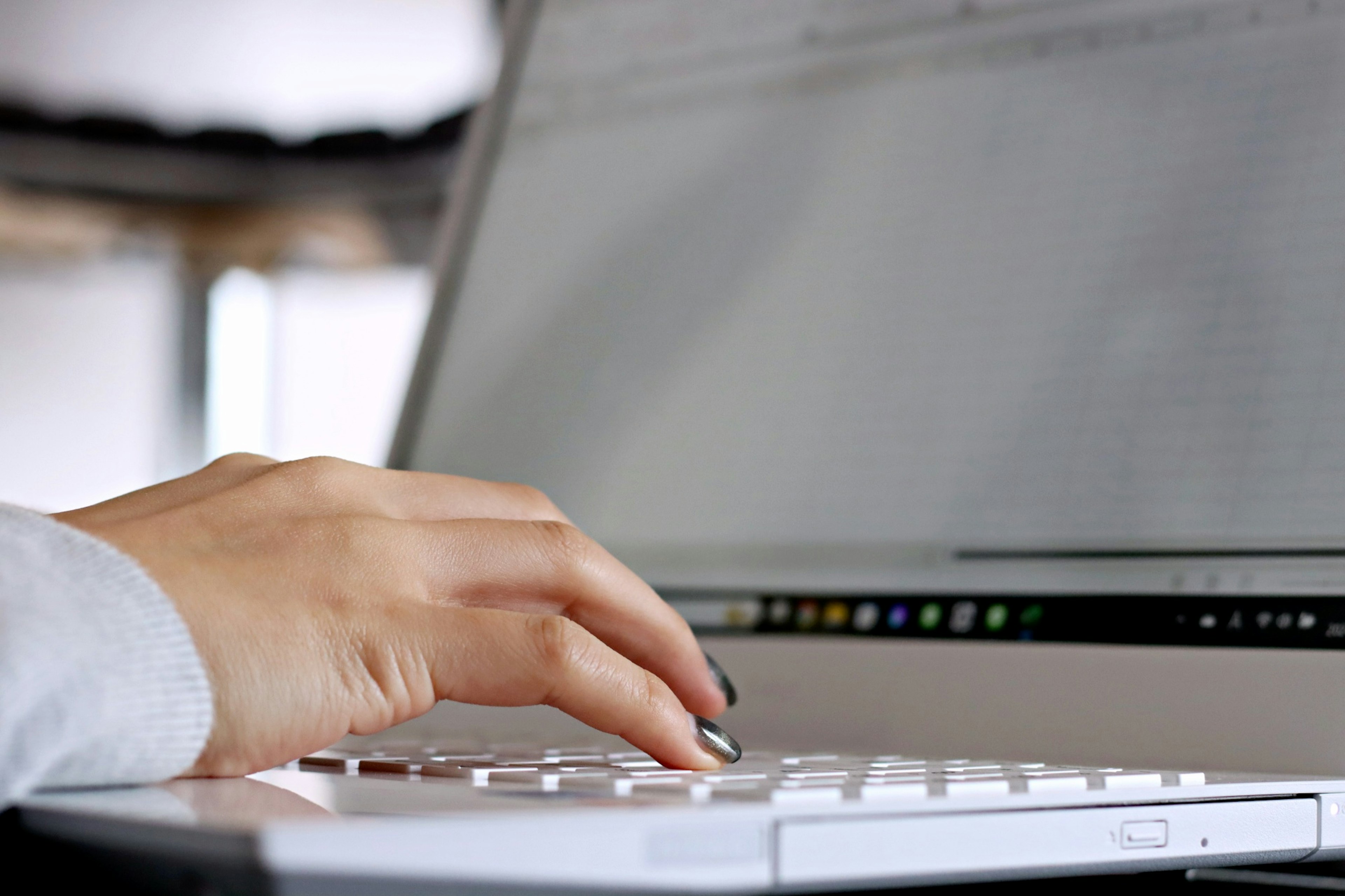 Main tapant sur le clavier d'un ordinateur portable blanc