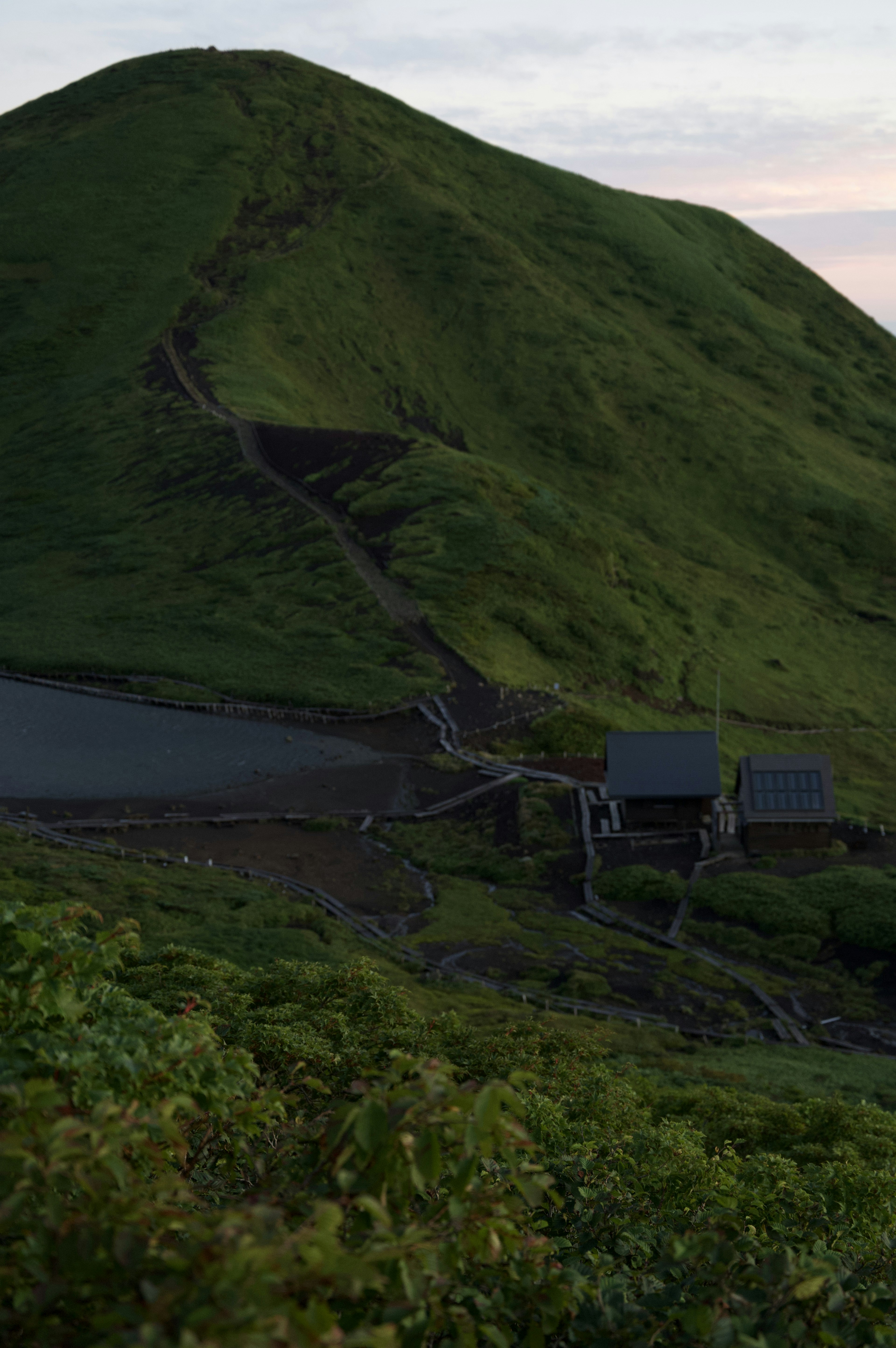 Scenic view of a green hill with a small building