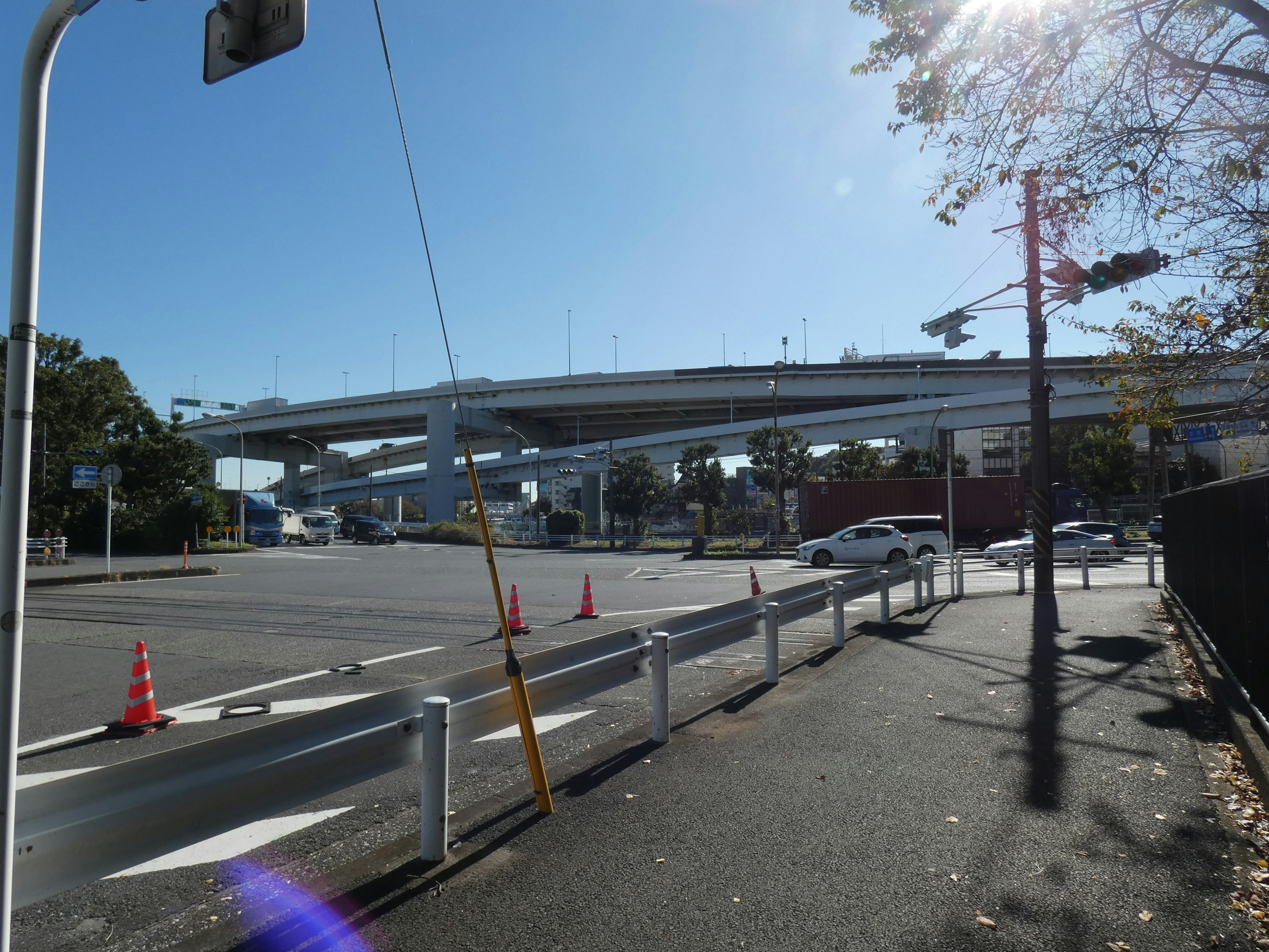 Jembatan layang di bawah langit biru cerah dengan lampu lalu lintas dan penghalang jalan