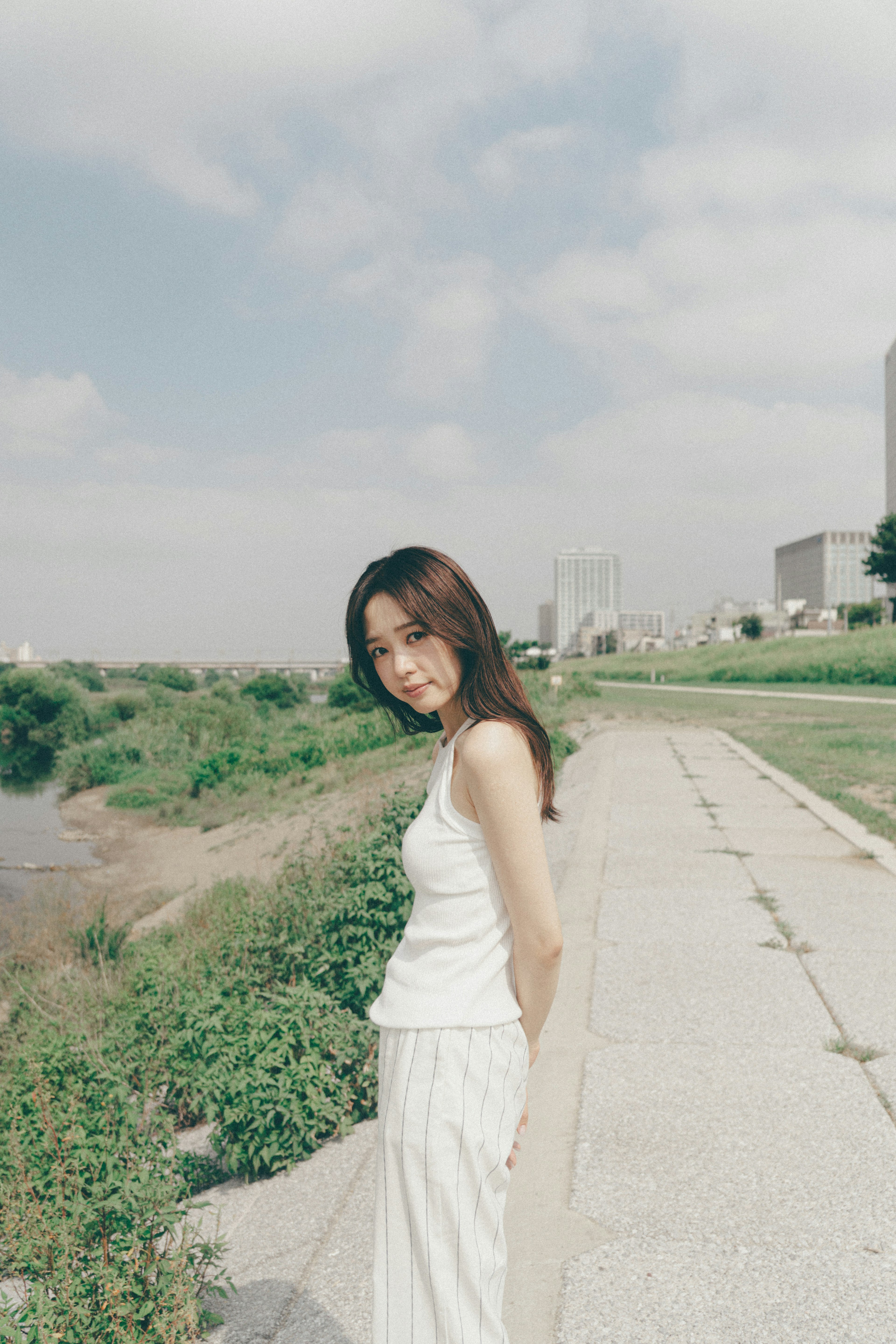 A woman in white clothing walking along a riverside path