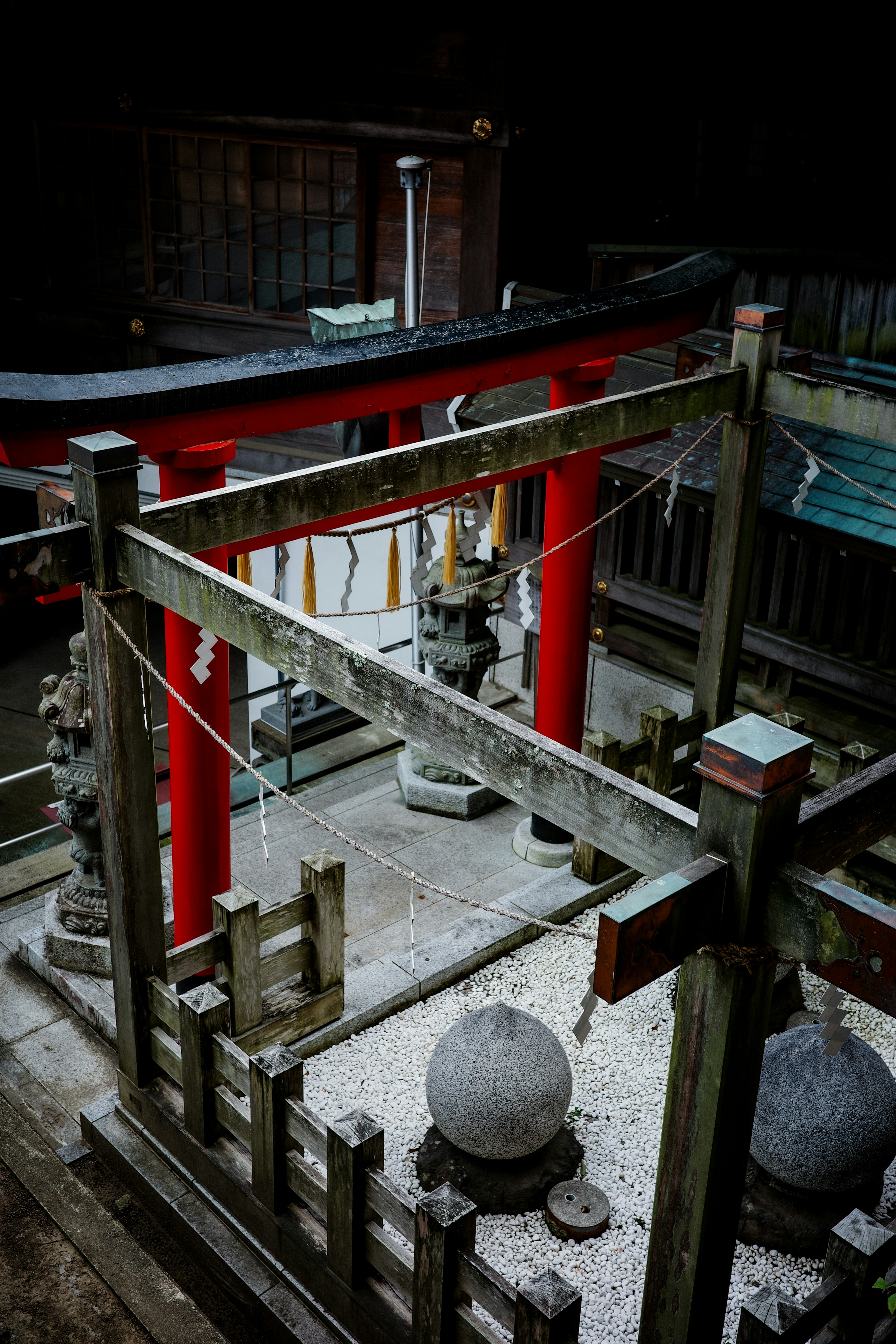 Interior view of a shrine featuring a red torii gate and stone lanterns