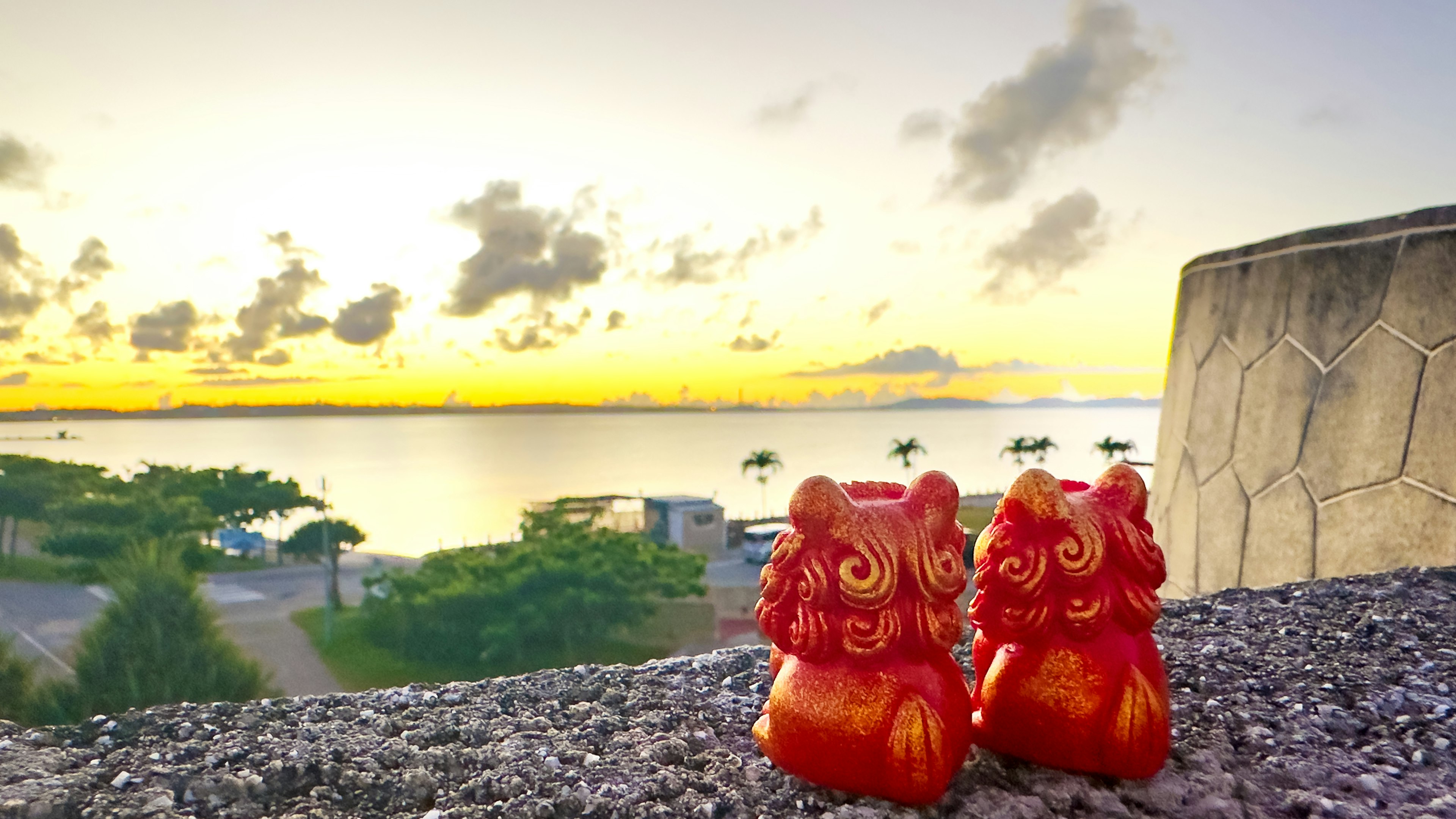 Dua patung singa merah dengan latar belakang matahari terbenam