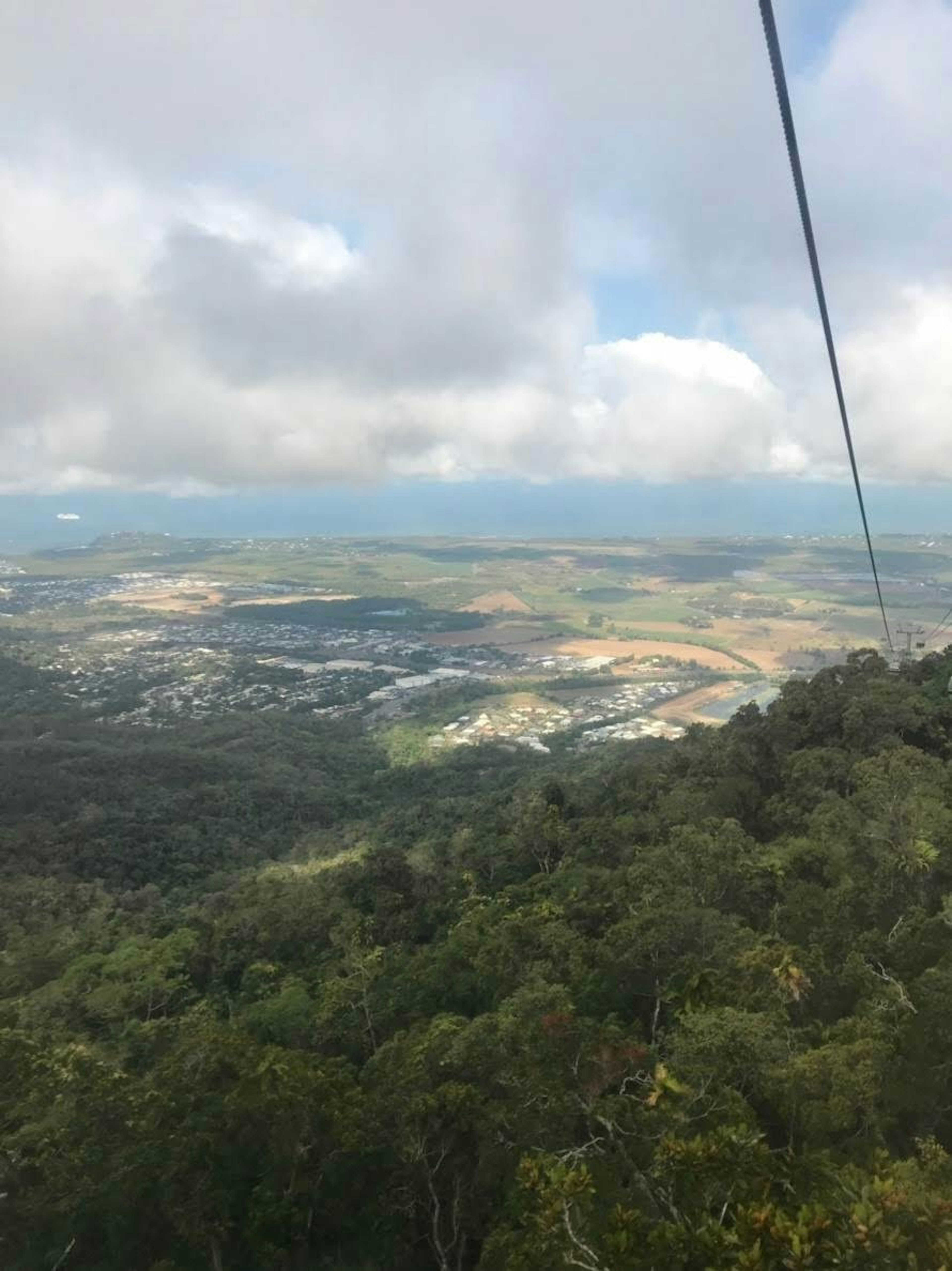 Scenic view from atop a mountain lush green trees and expansive land beneath cloudy skies