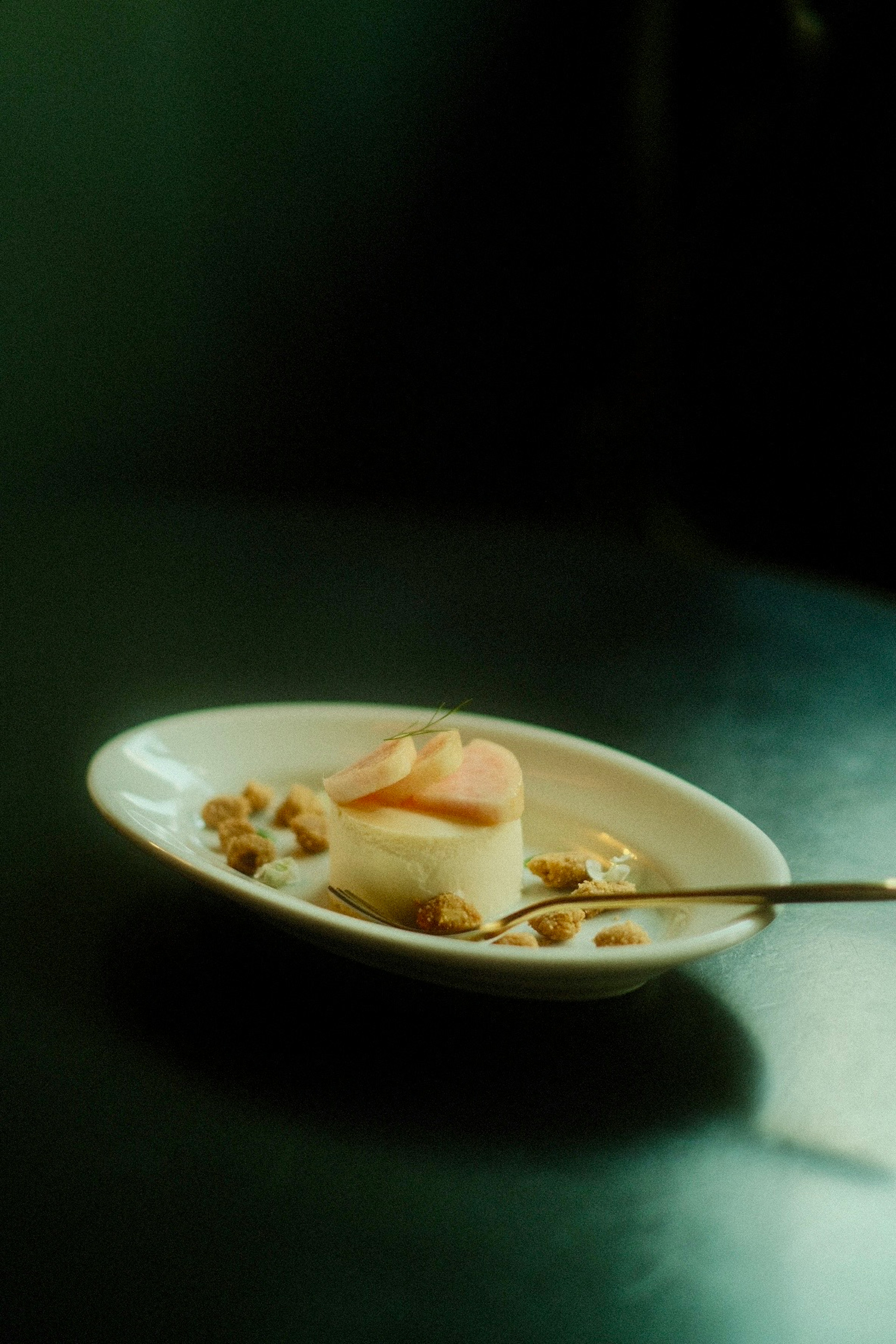 Postre servido en un plato blanco con nueces y una cuchara dorada