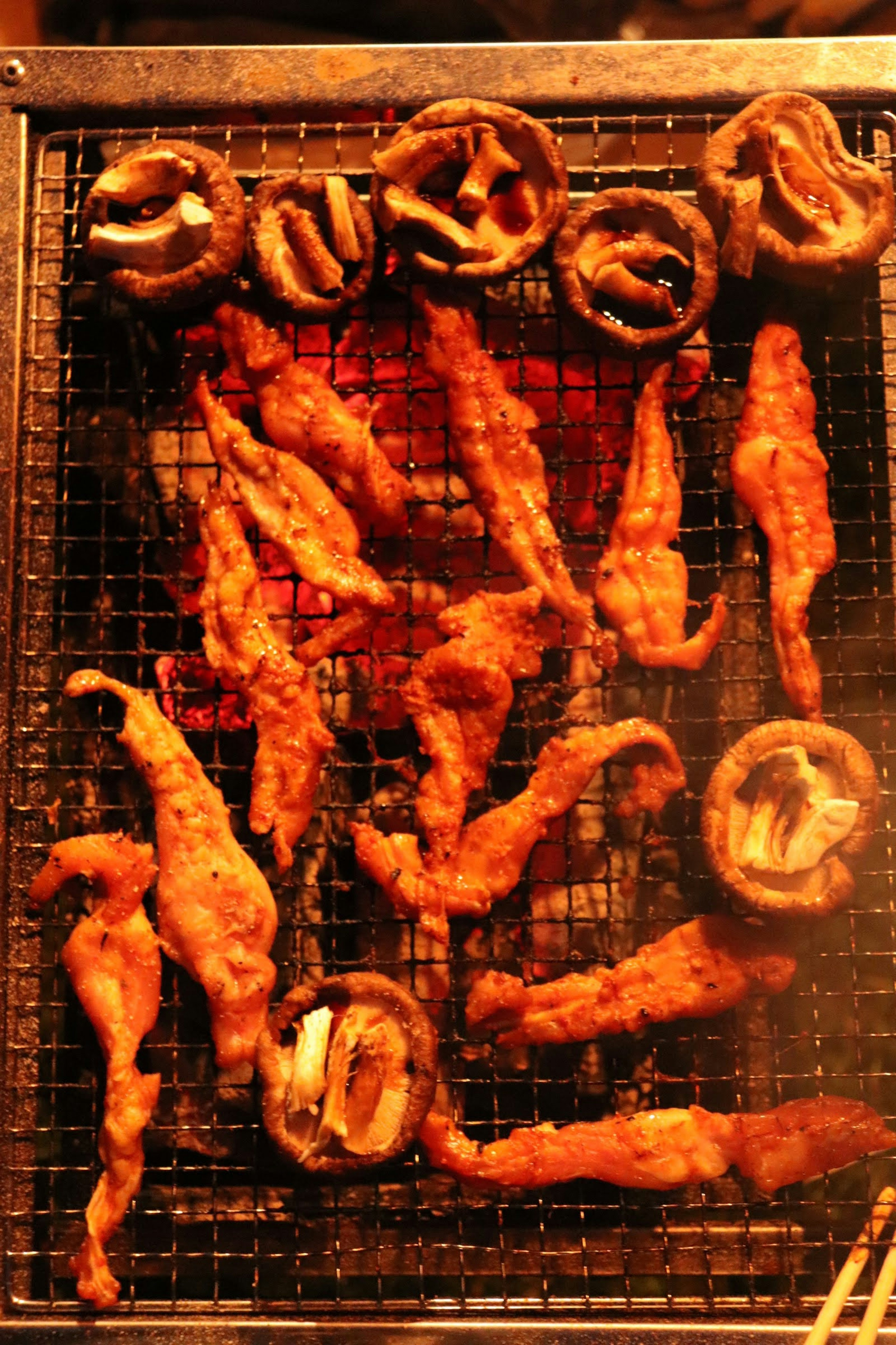 Grilled chicken pieces and mushrooms cooking on a wire rack