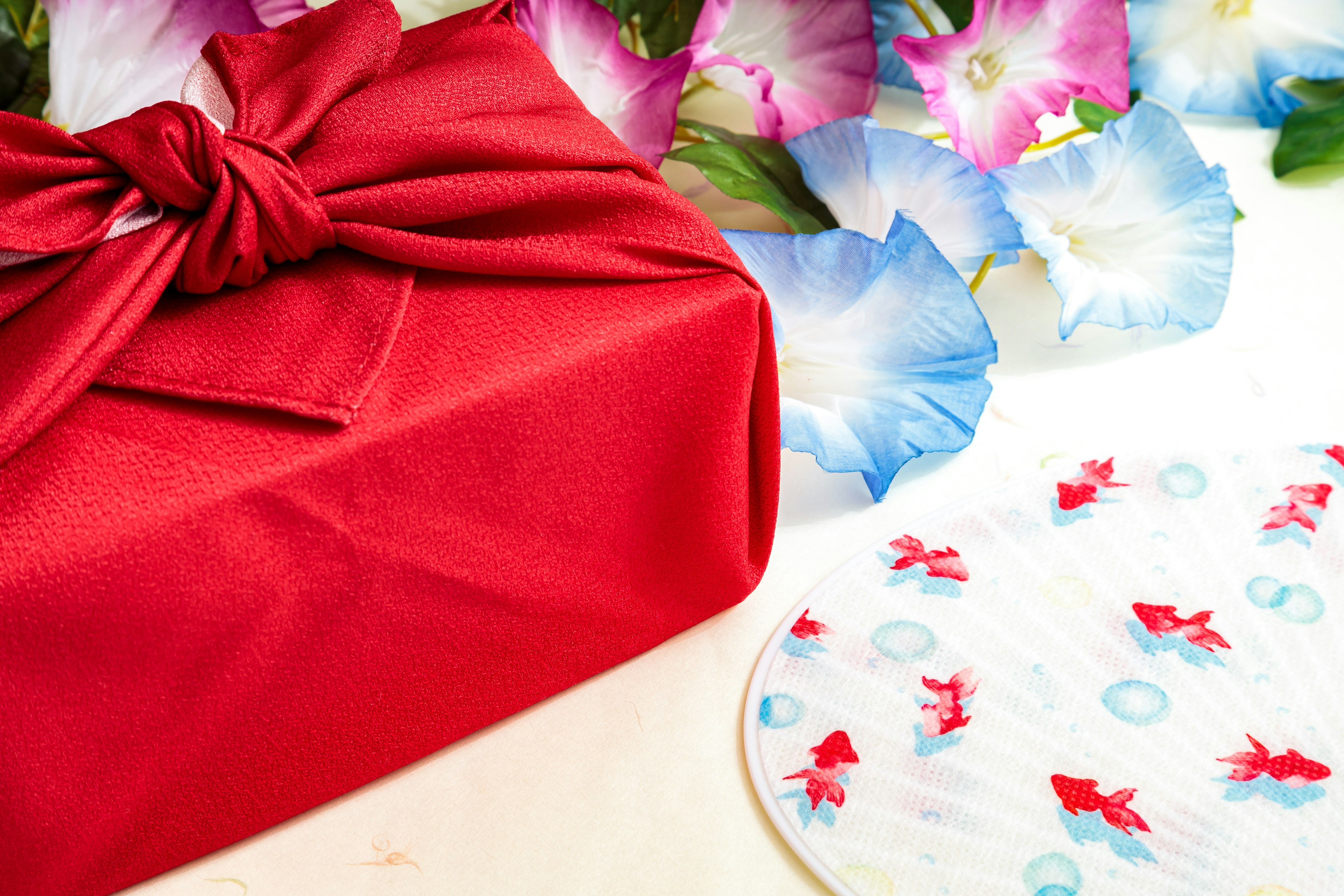 A red wrapped gift with floral decorations and a patterned cloth