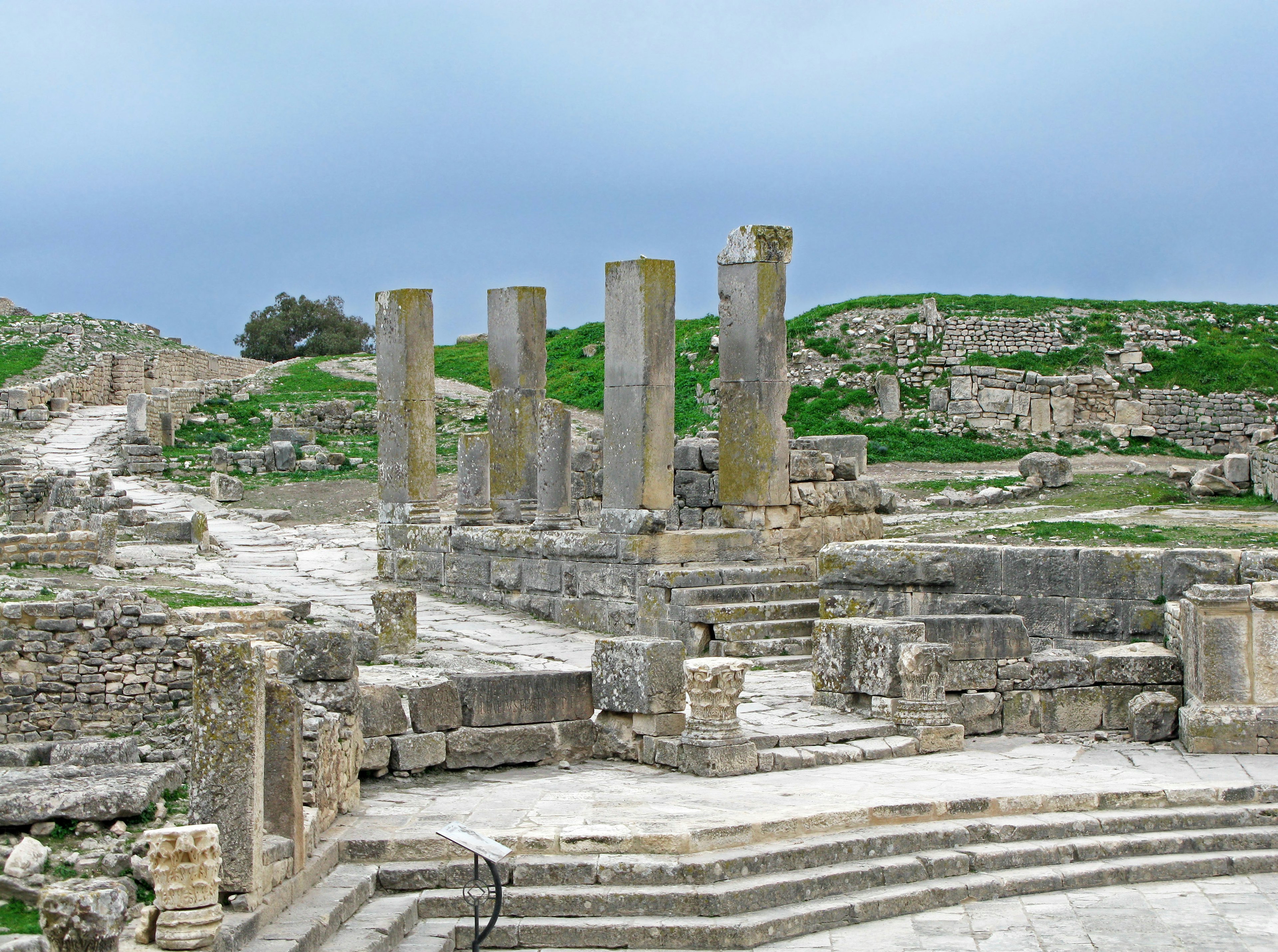 Paisaje con ruinas antiguas que incluyen columnas y escaleras de piedra