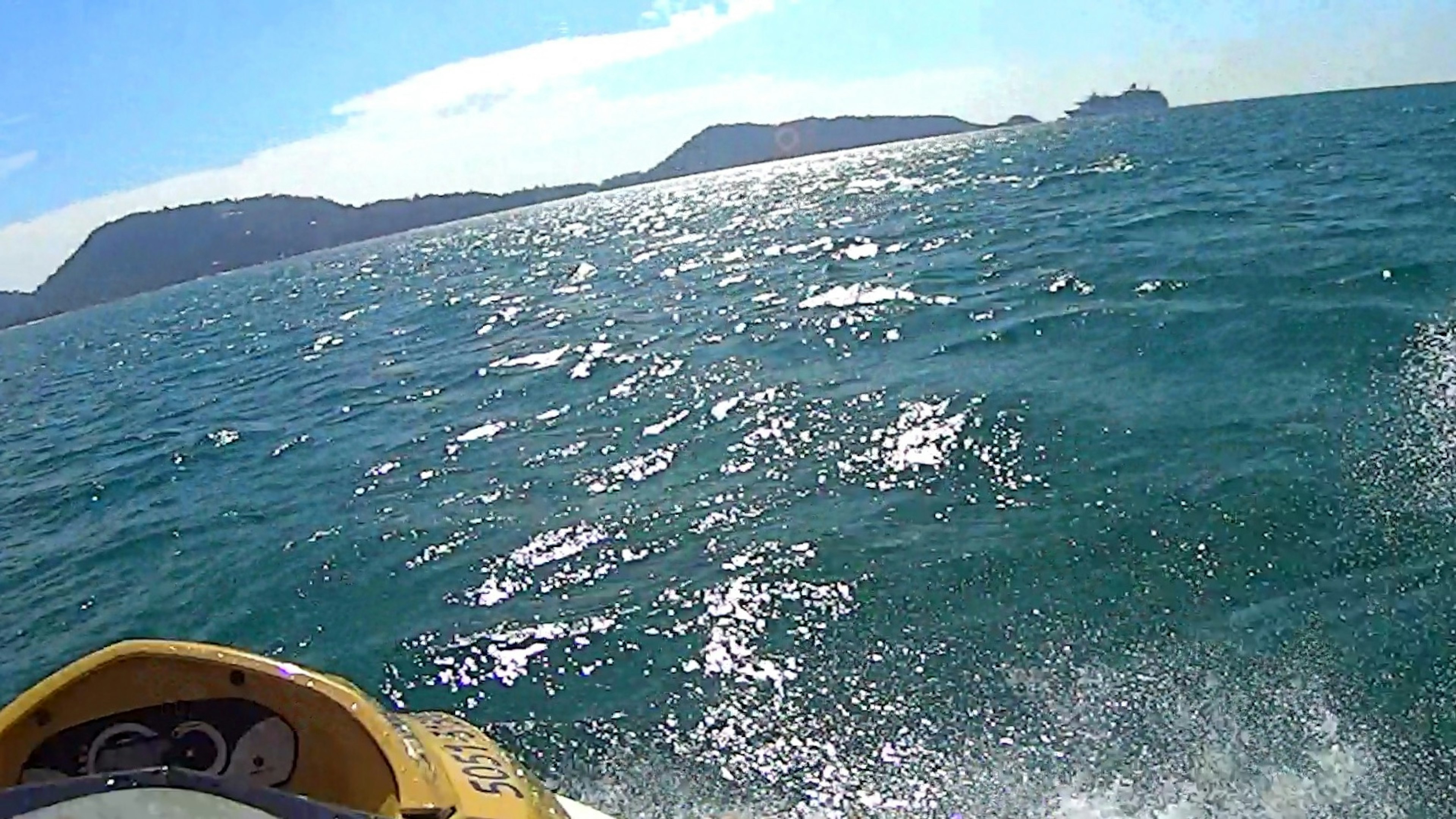 Jet ski splashing through blue ocean waves with distant islands