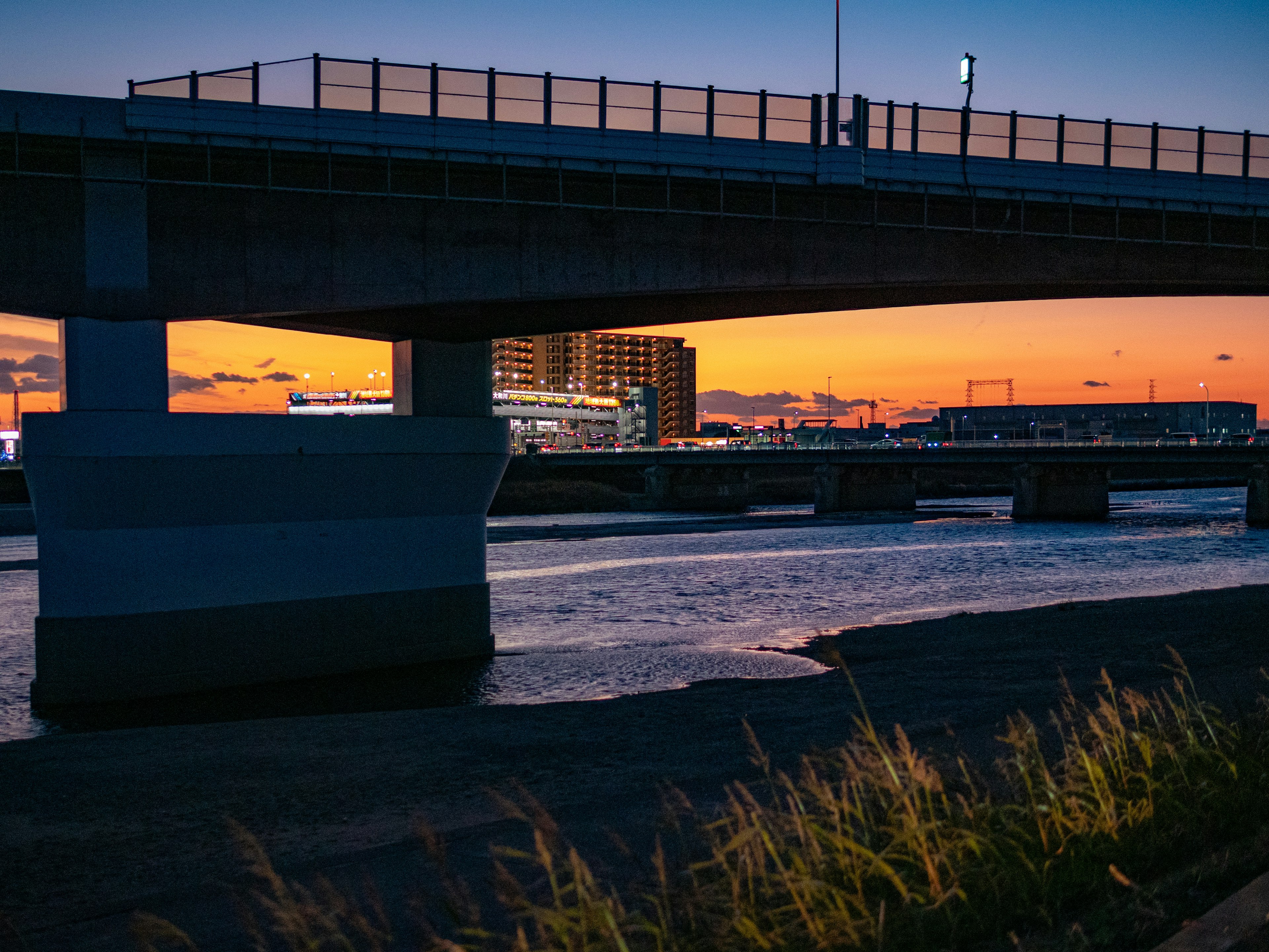 Ponte che attraversa un fiume al tramonto con sfondo urbano