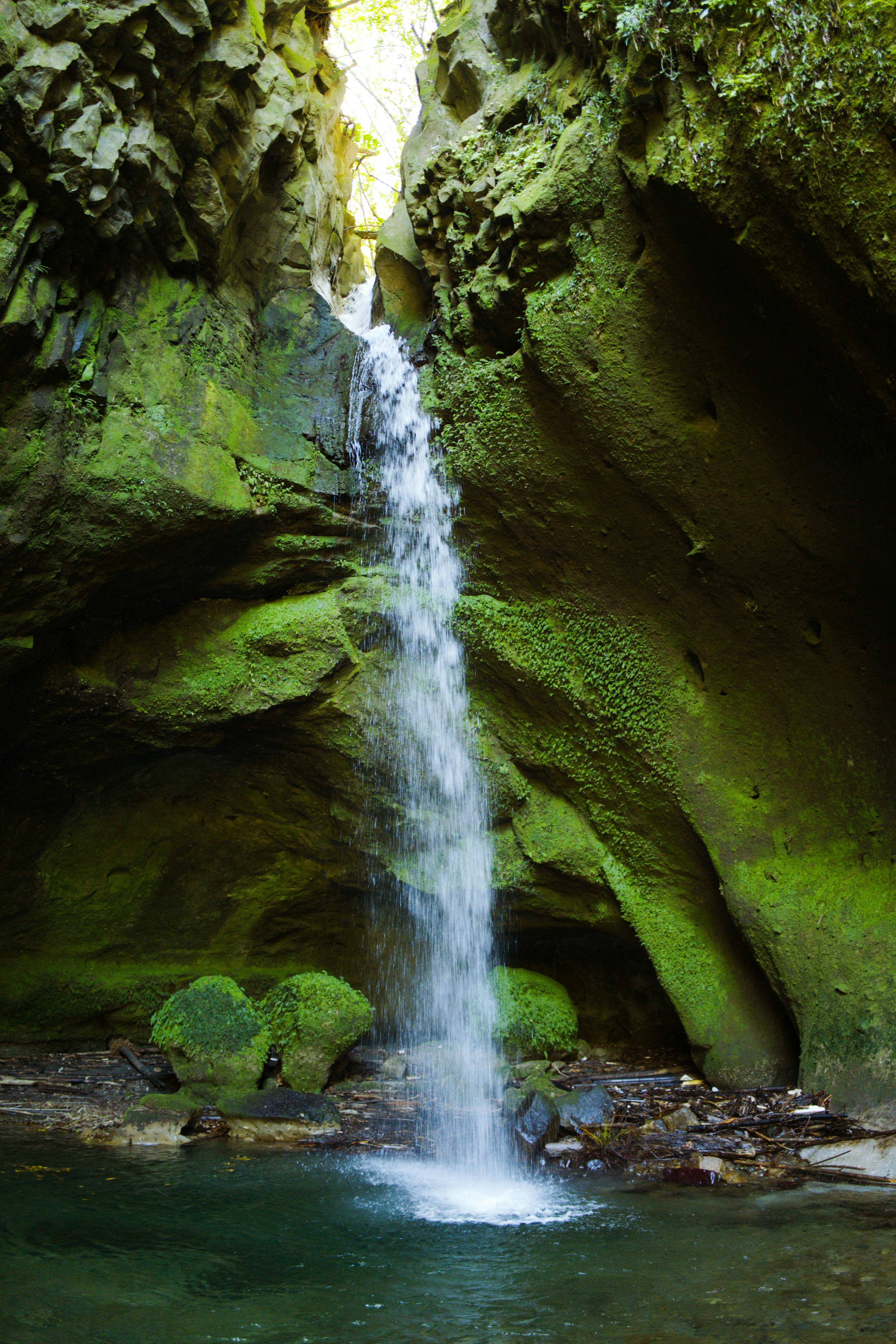 A beautiful scene of a waterfall cascading over a green-covered cliff