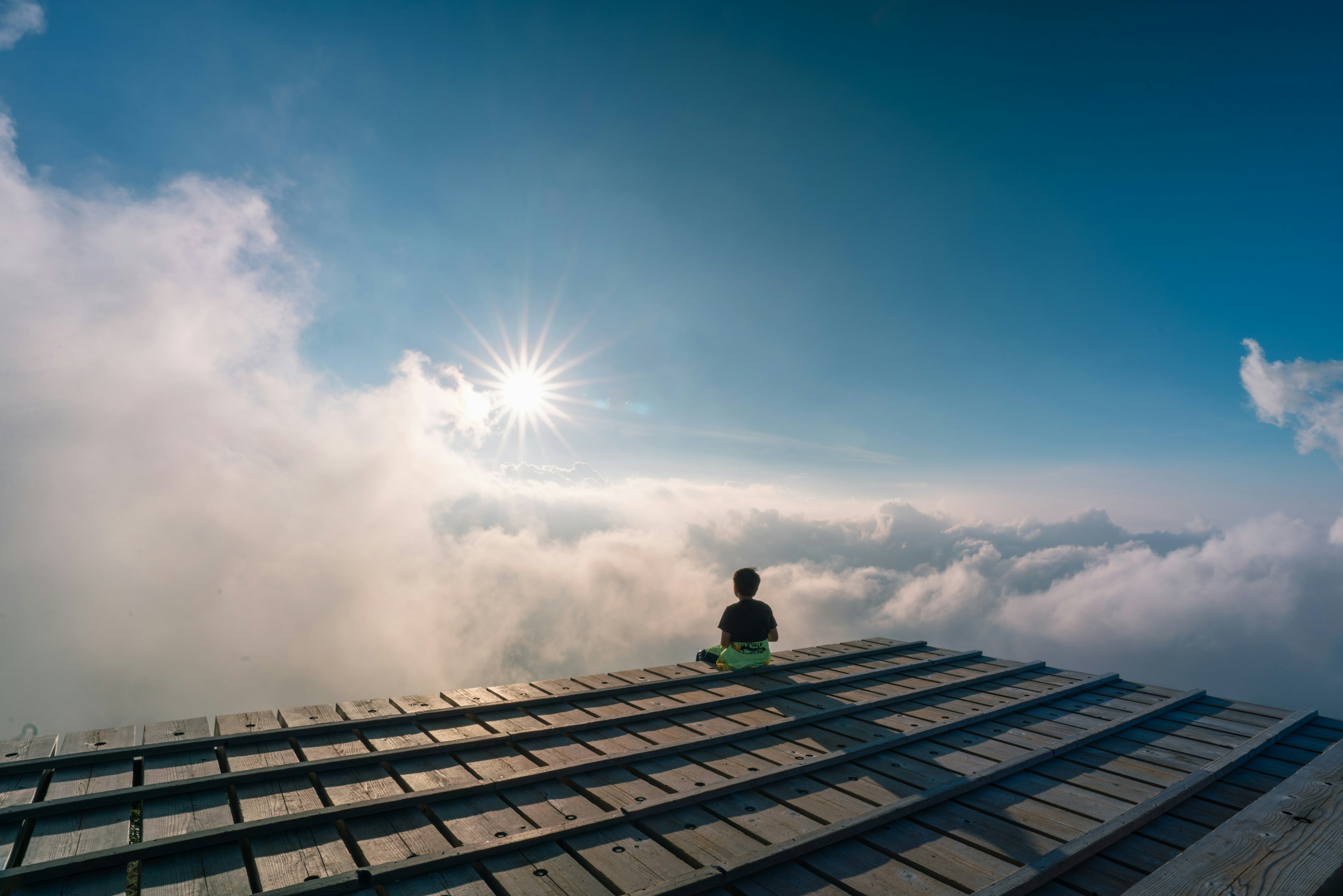 雲の上に座る人物と明るい太陽