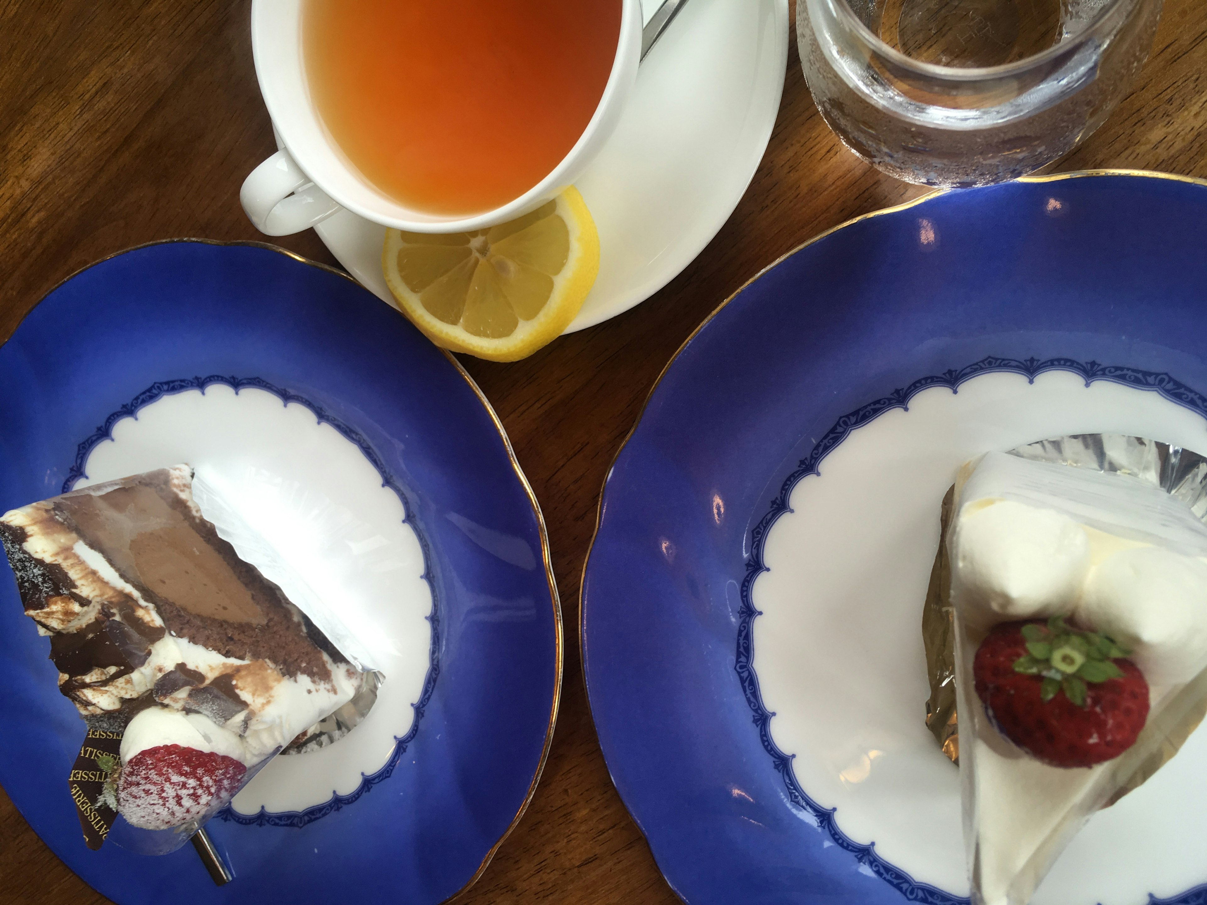 Desserts on blue plates accompanied by tea and lemon