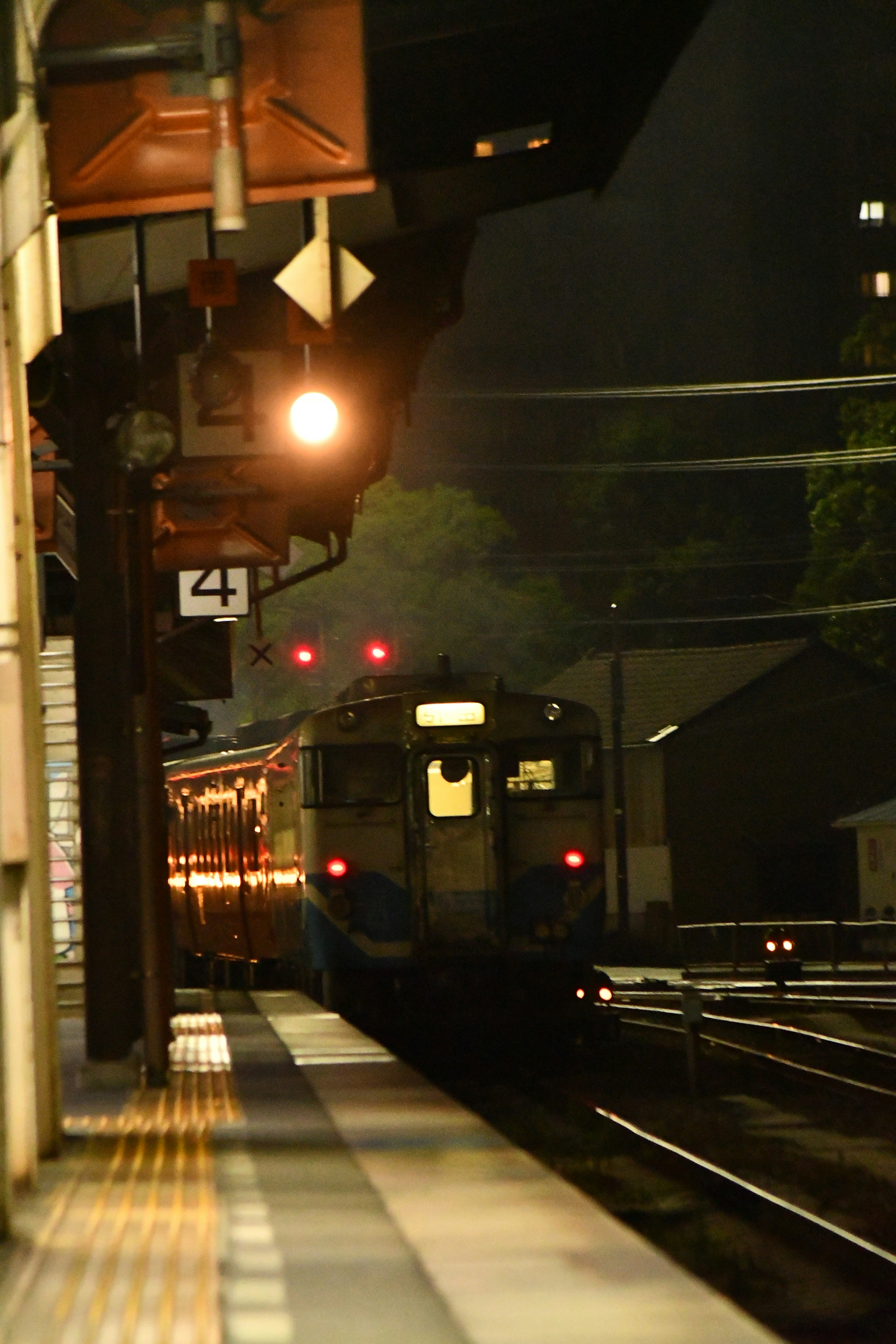 Train stopped at a station at night with platform lighting