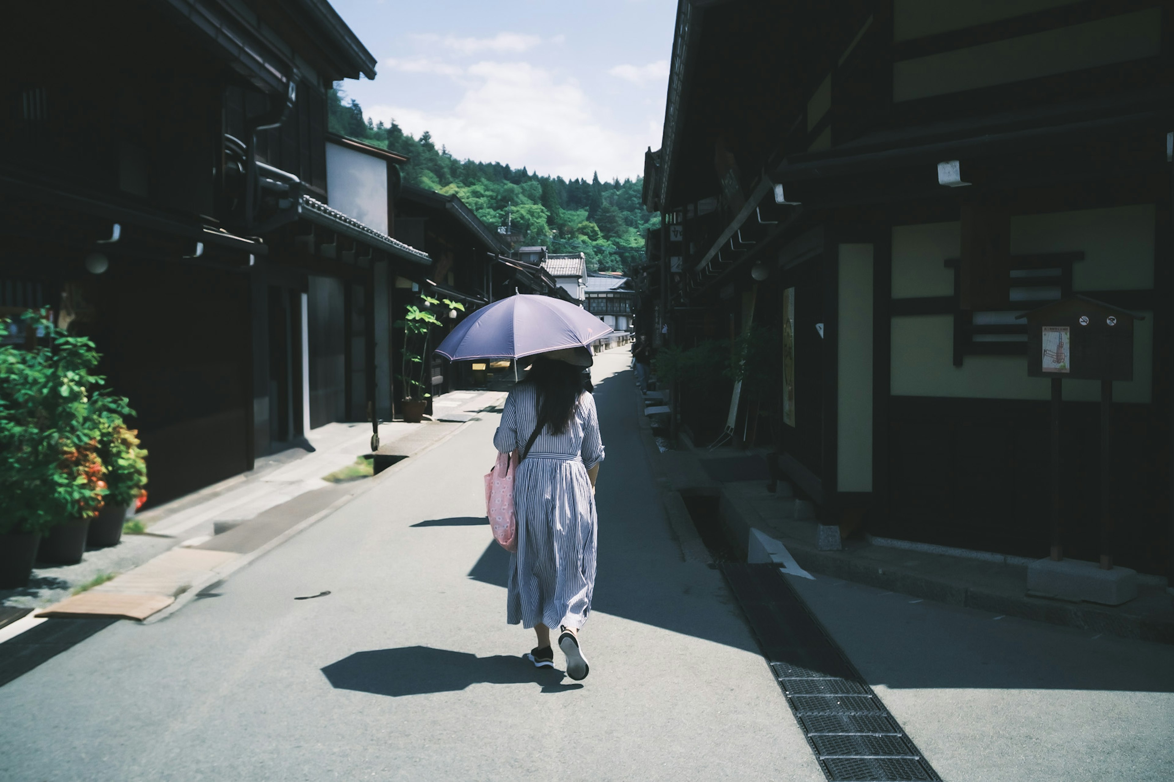 女性が傘を持って古い街を歩いている風景