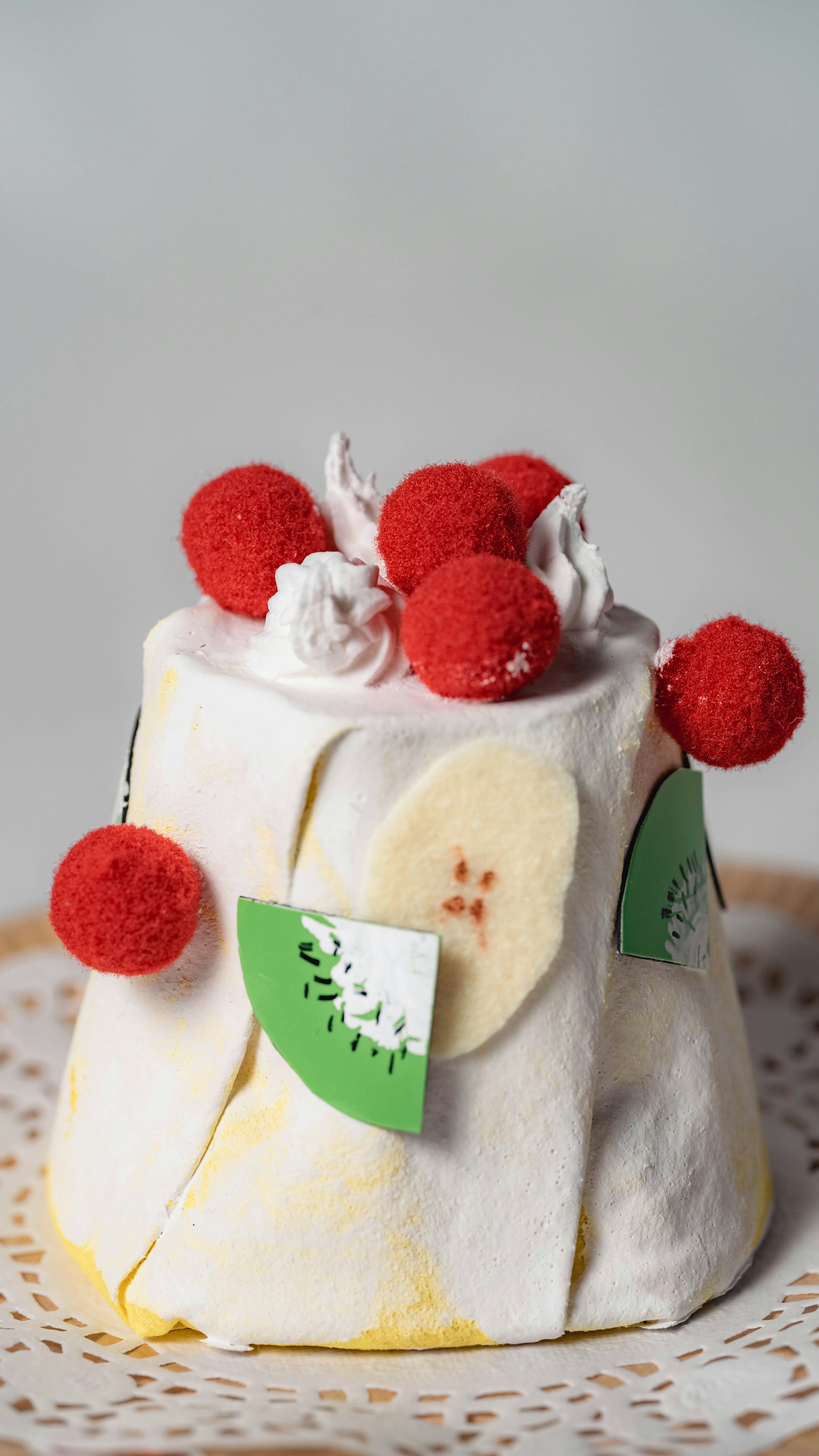 A cute cake topped with white cream and red fruits