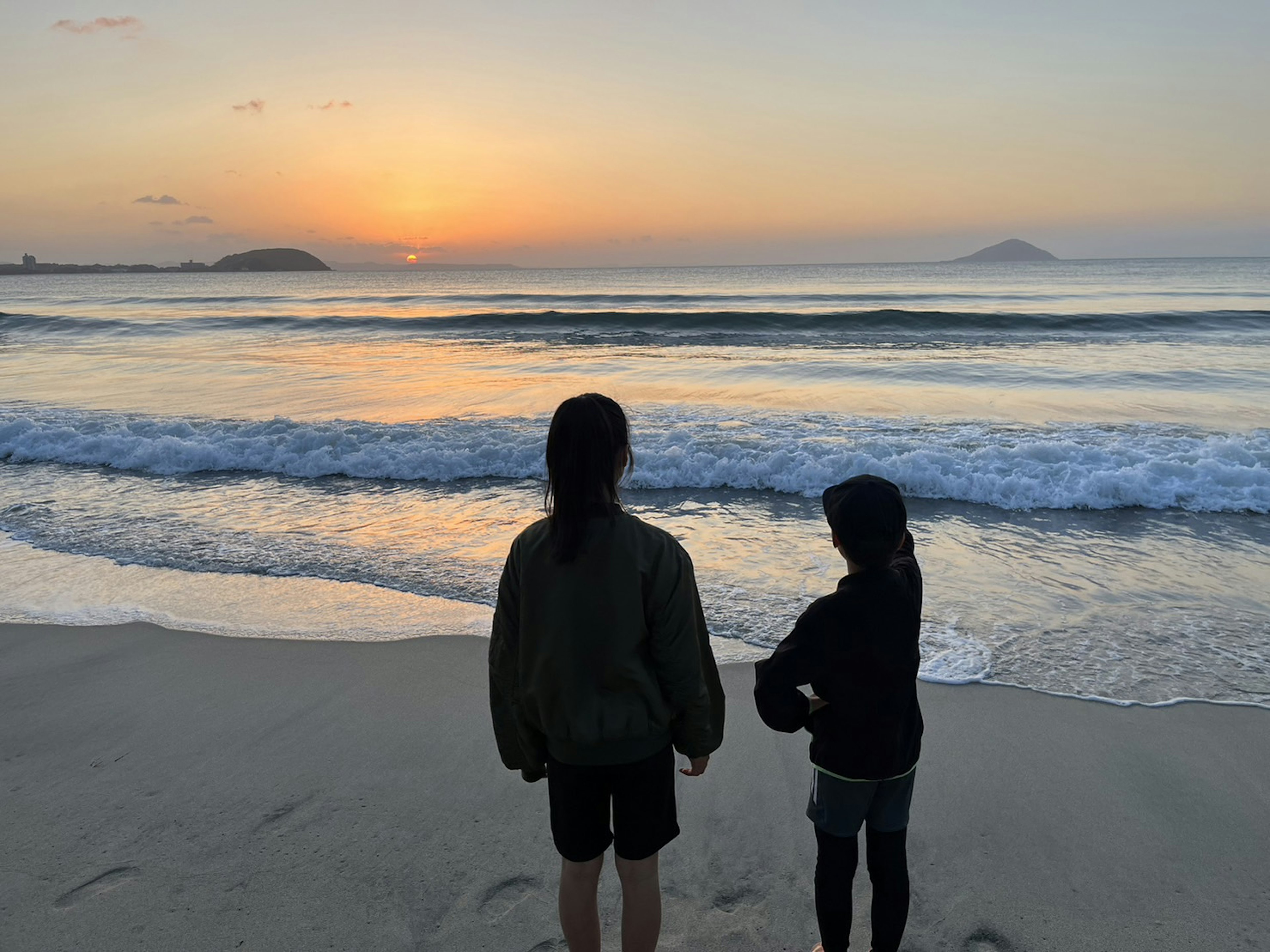 Zwei Kinder beobachten den Sonnenuntergang am Strand