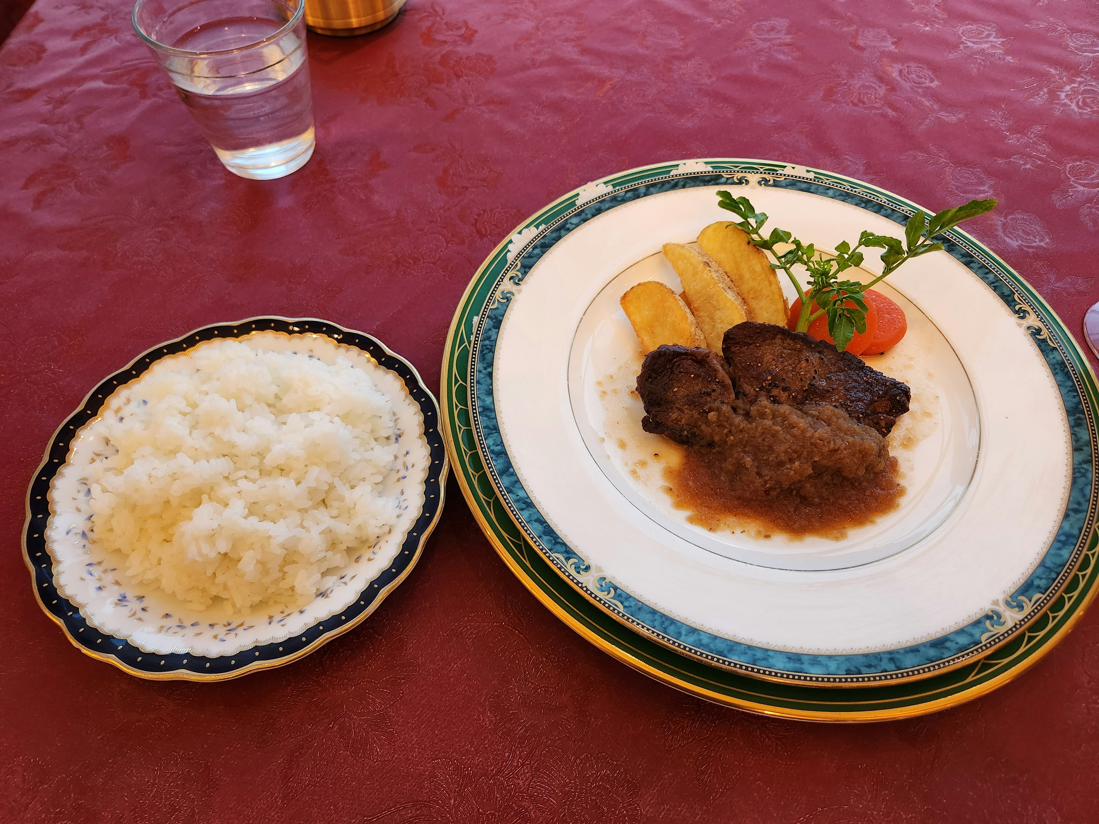 Piring dengan hidangan daging disertai pisang dan semangkuk kecil nasi