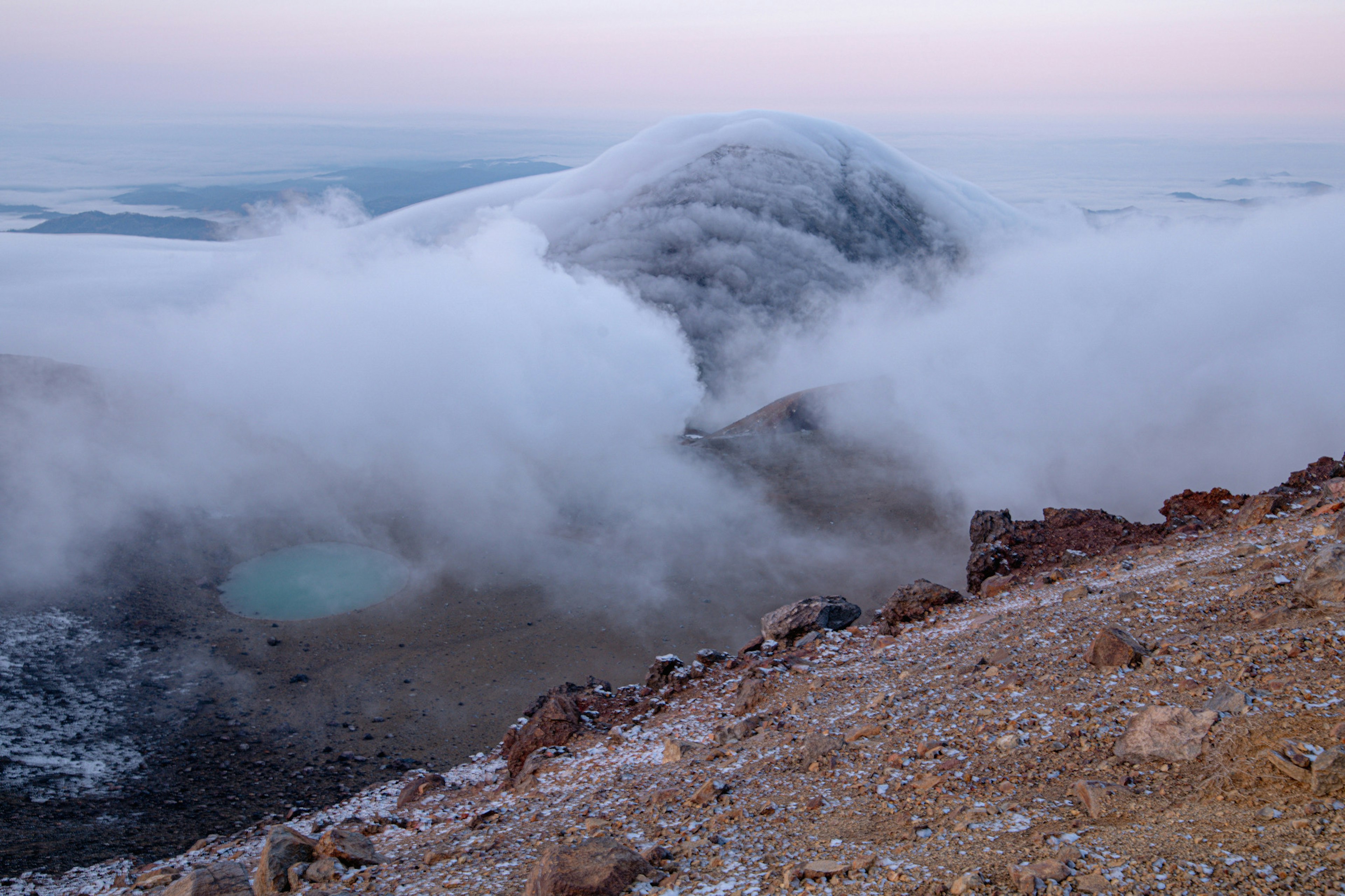 山の頂上からの景色 雲に覆われた山の輪郭と静かな湖が見える