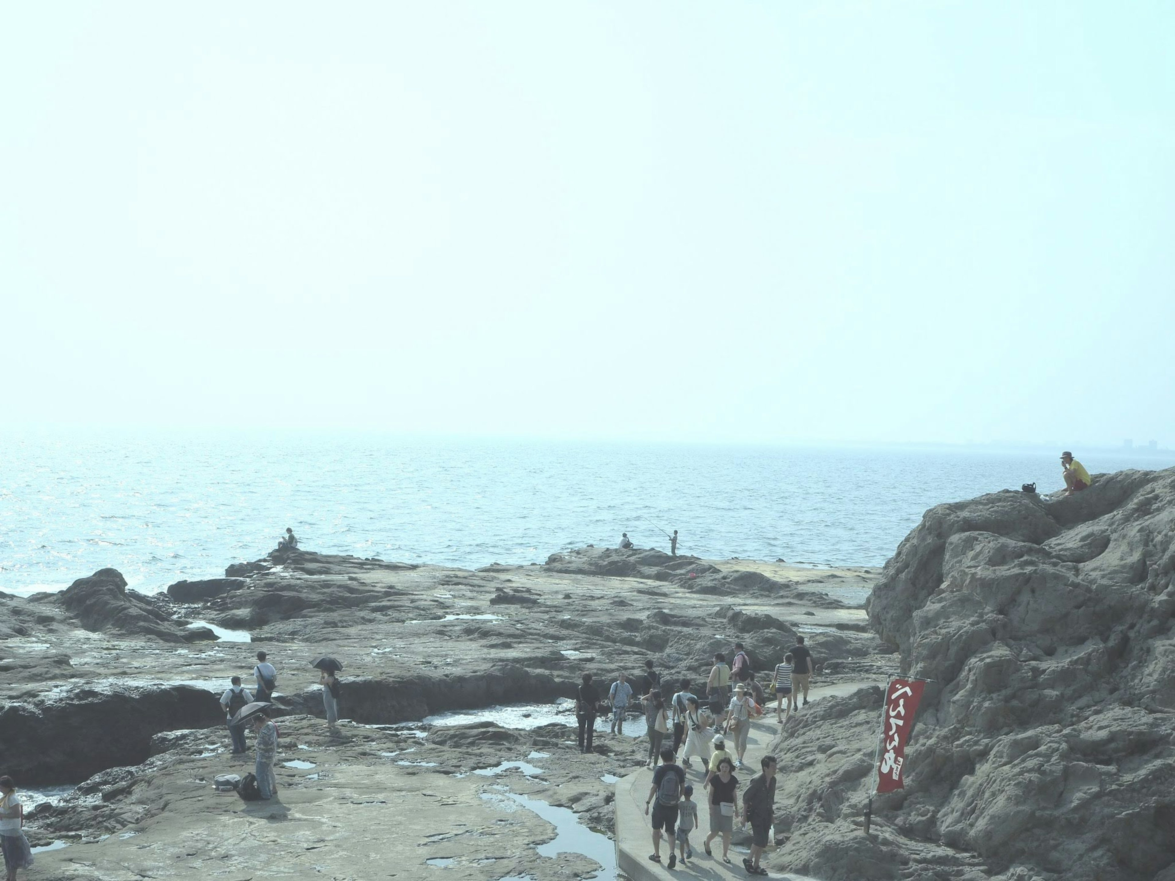 Gathering of people with ocean and rocky background