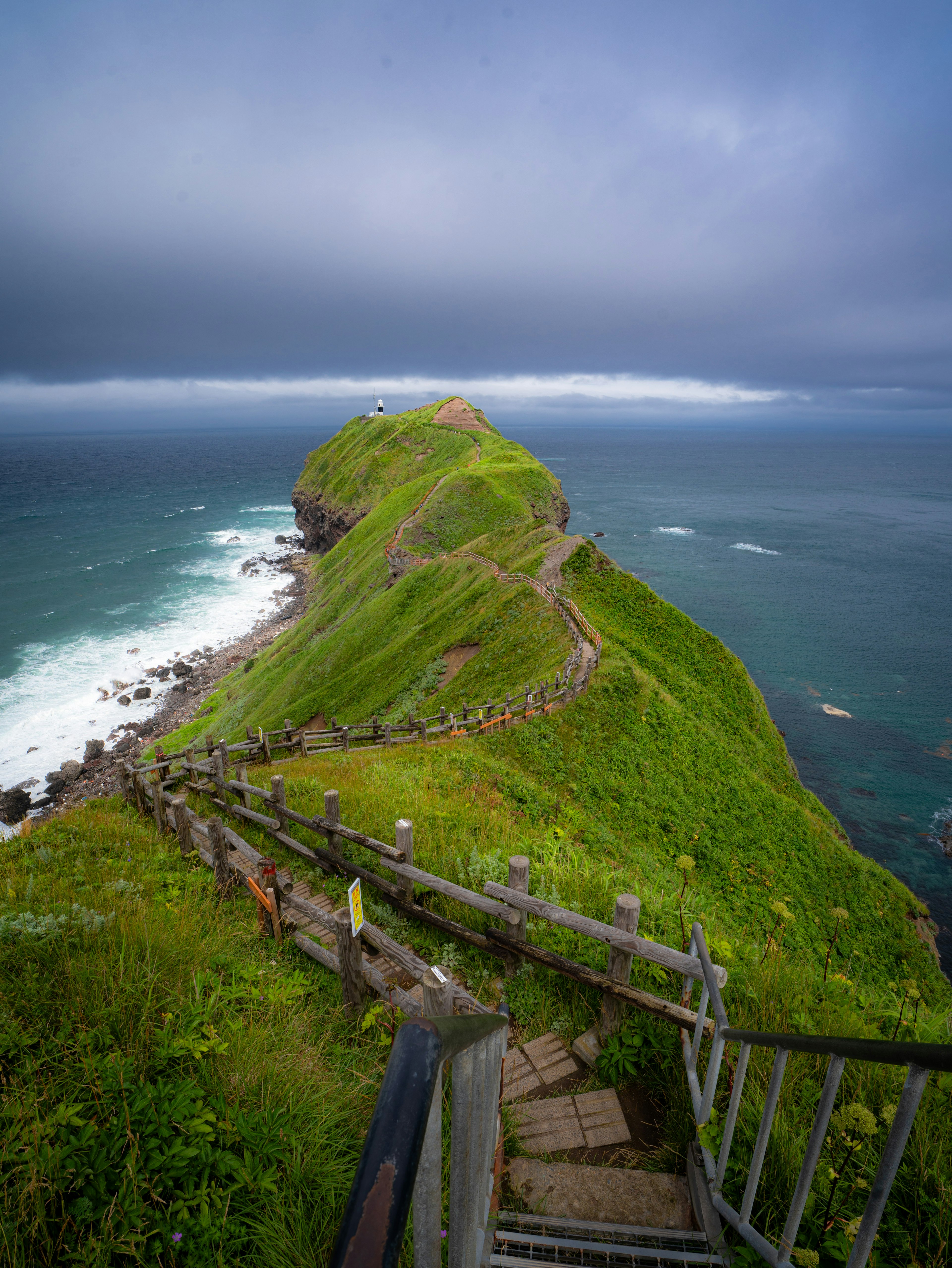 Escalier menant à une colline verte surplombant l'océan