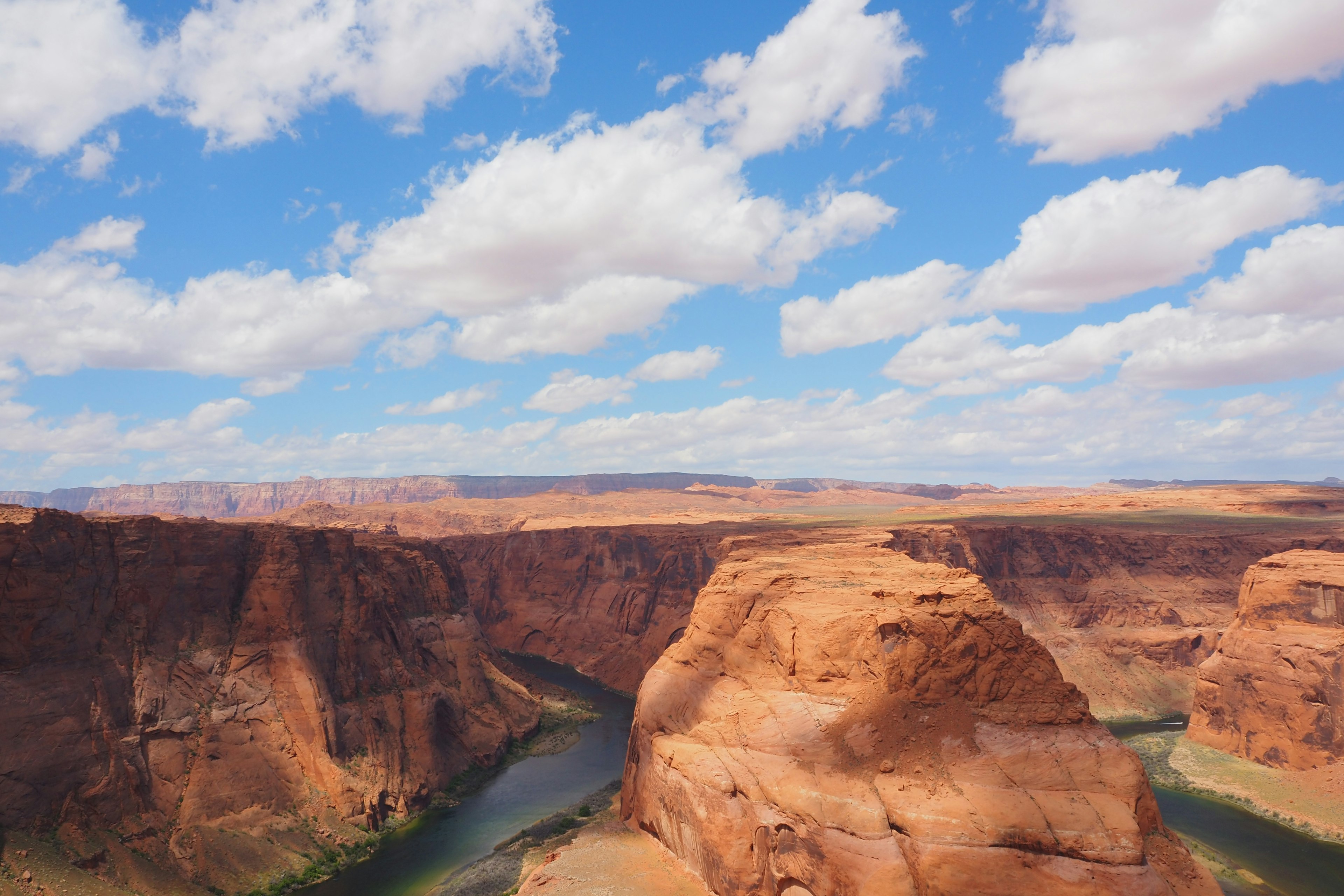 Vue pittoresque d'un canyon de roches rouges et d'une rivière sous un ciel bleu avec des nuages moelleux