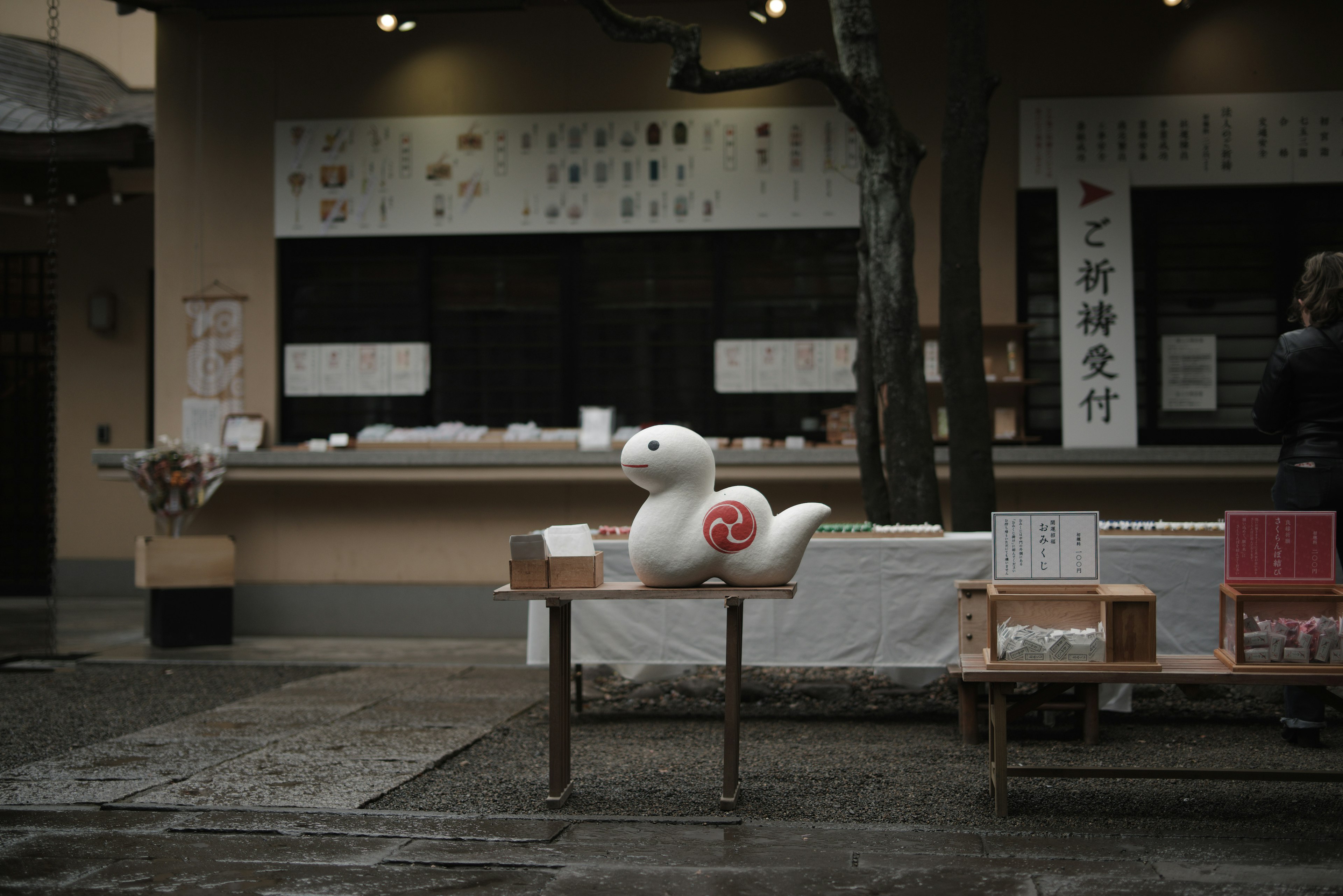 Una figura de caracol blanca colocada sobre una mesa frente a una tienda japonesa tradicional