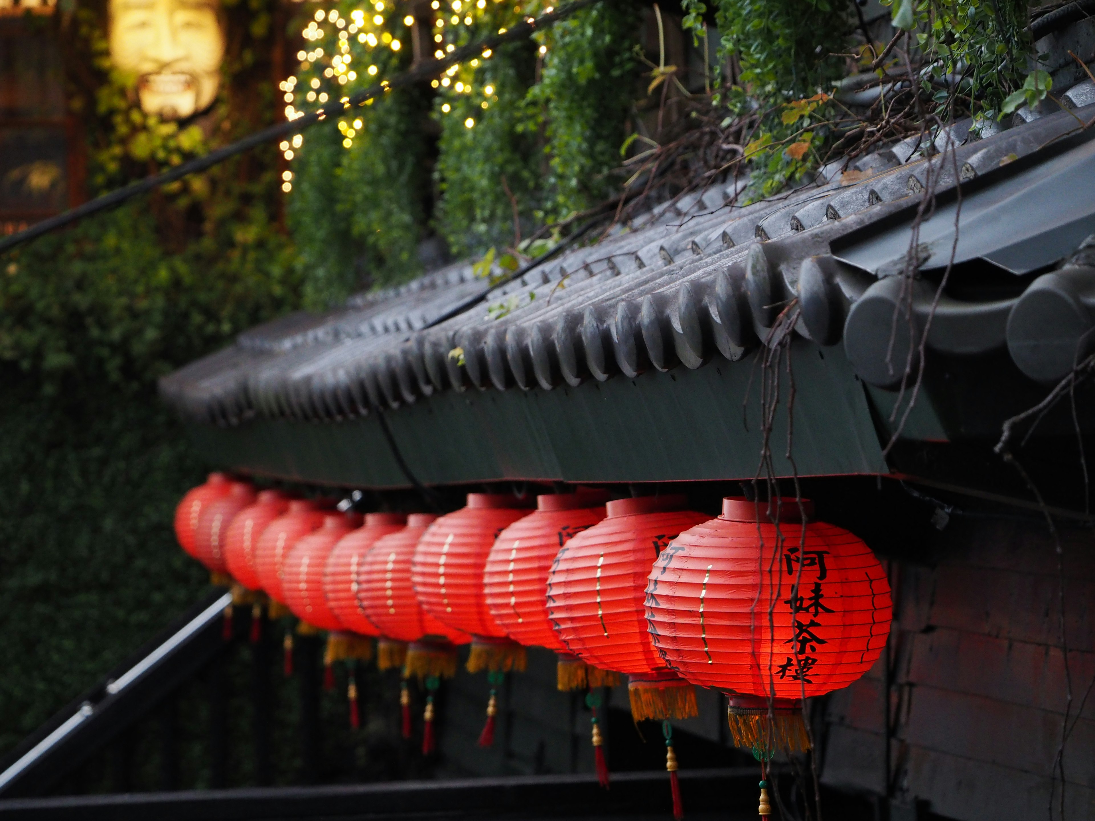 Row of red lanterns hanging under a roof at night