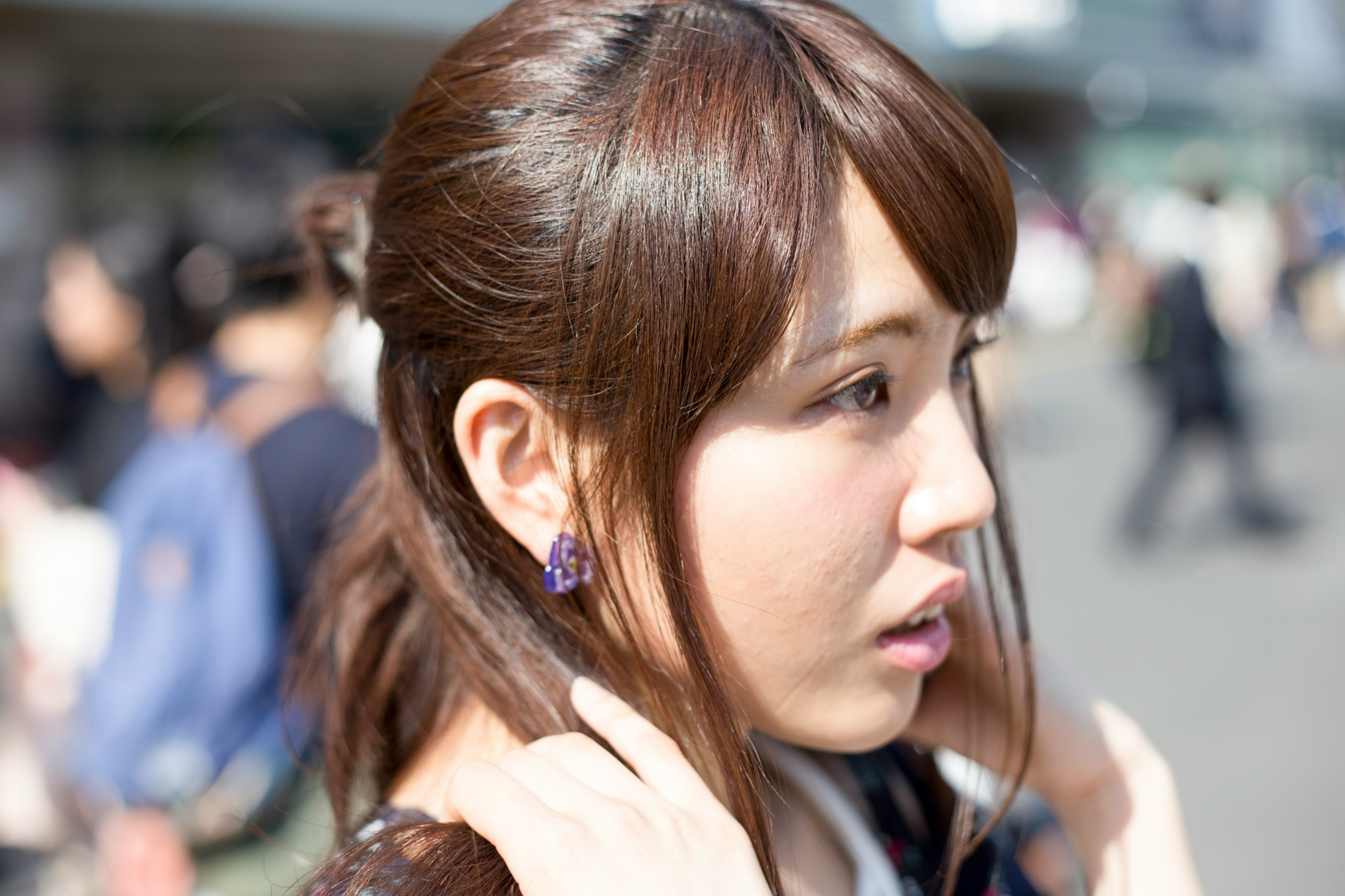 A woman adjusting her hair while standing in a busy street