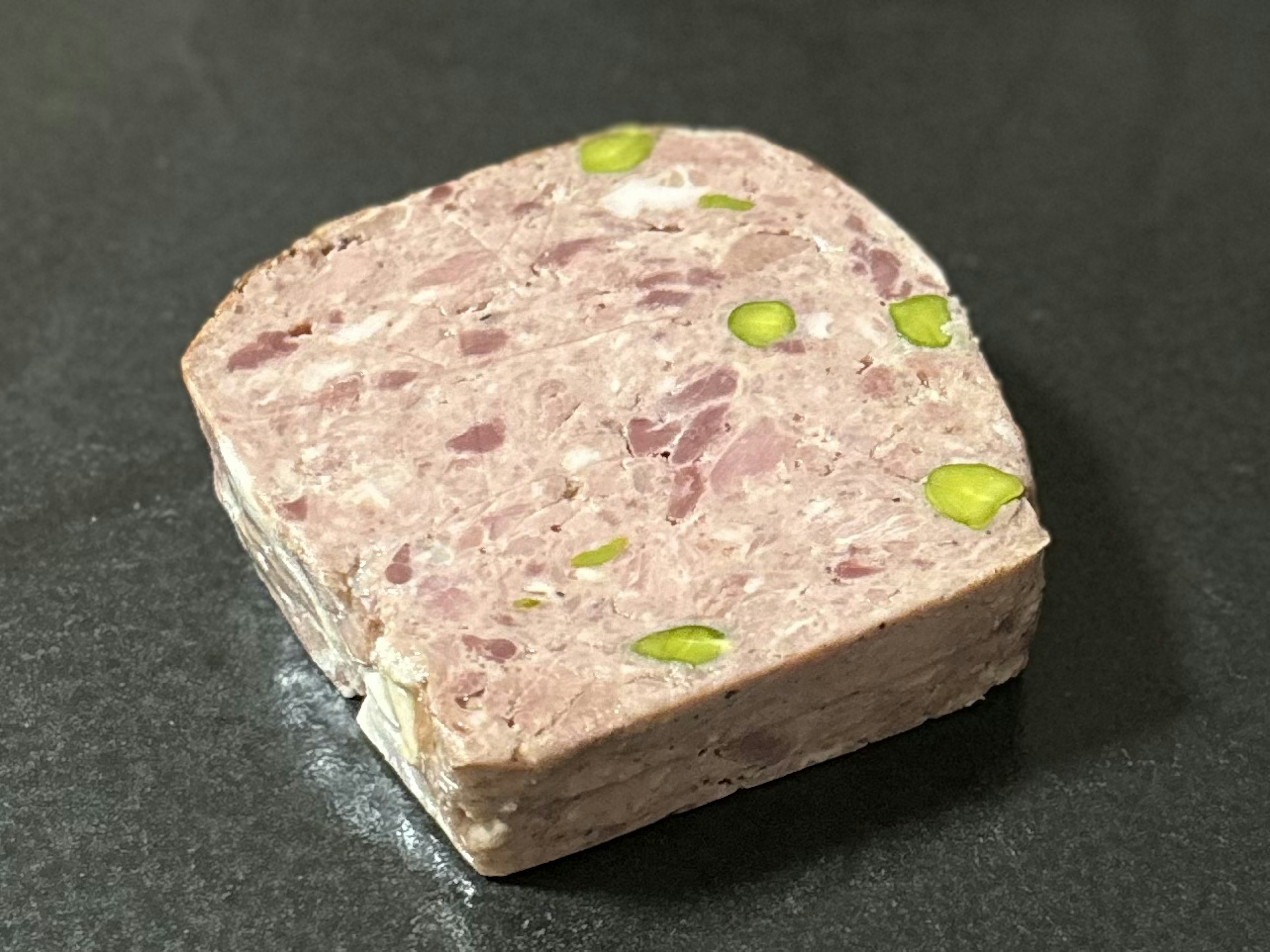 Terrine de viande rose pâle avec des morceaux de pistache verte