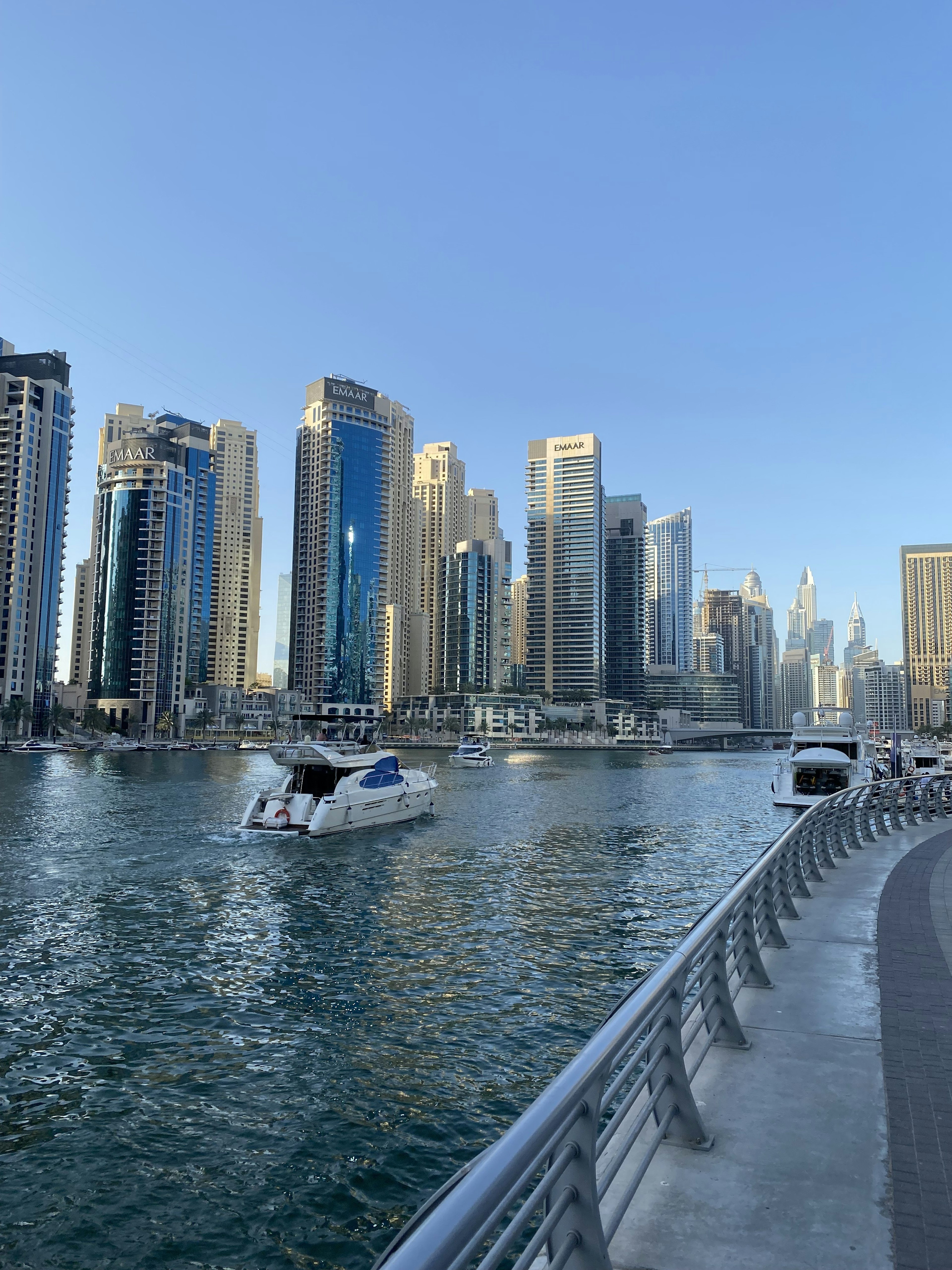 Blick auf die Wolkenkratzer von Dubai entlang der Uferpromenade mit einem Boot