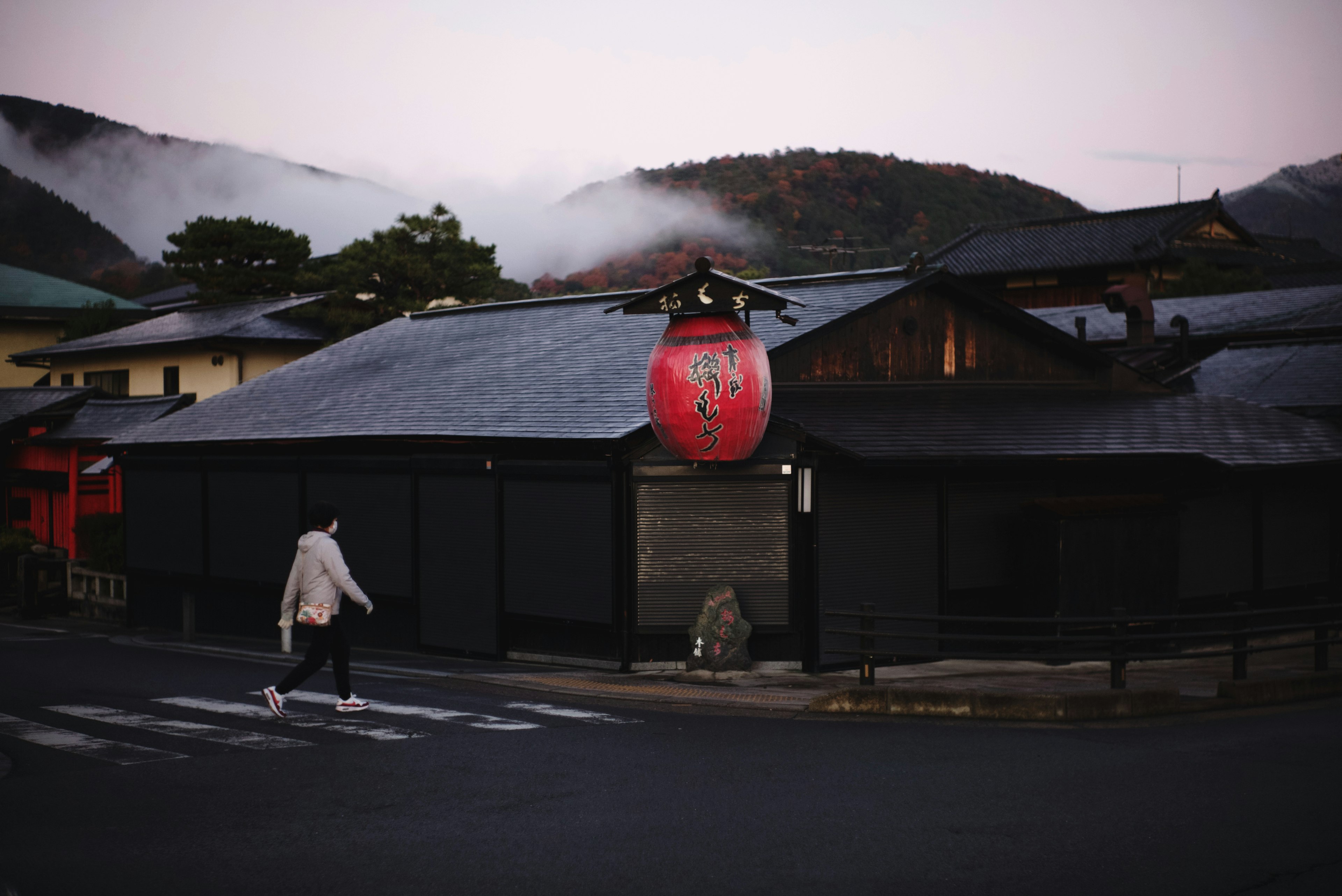 Traditional Japanese black building with a red lantern at dusk