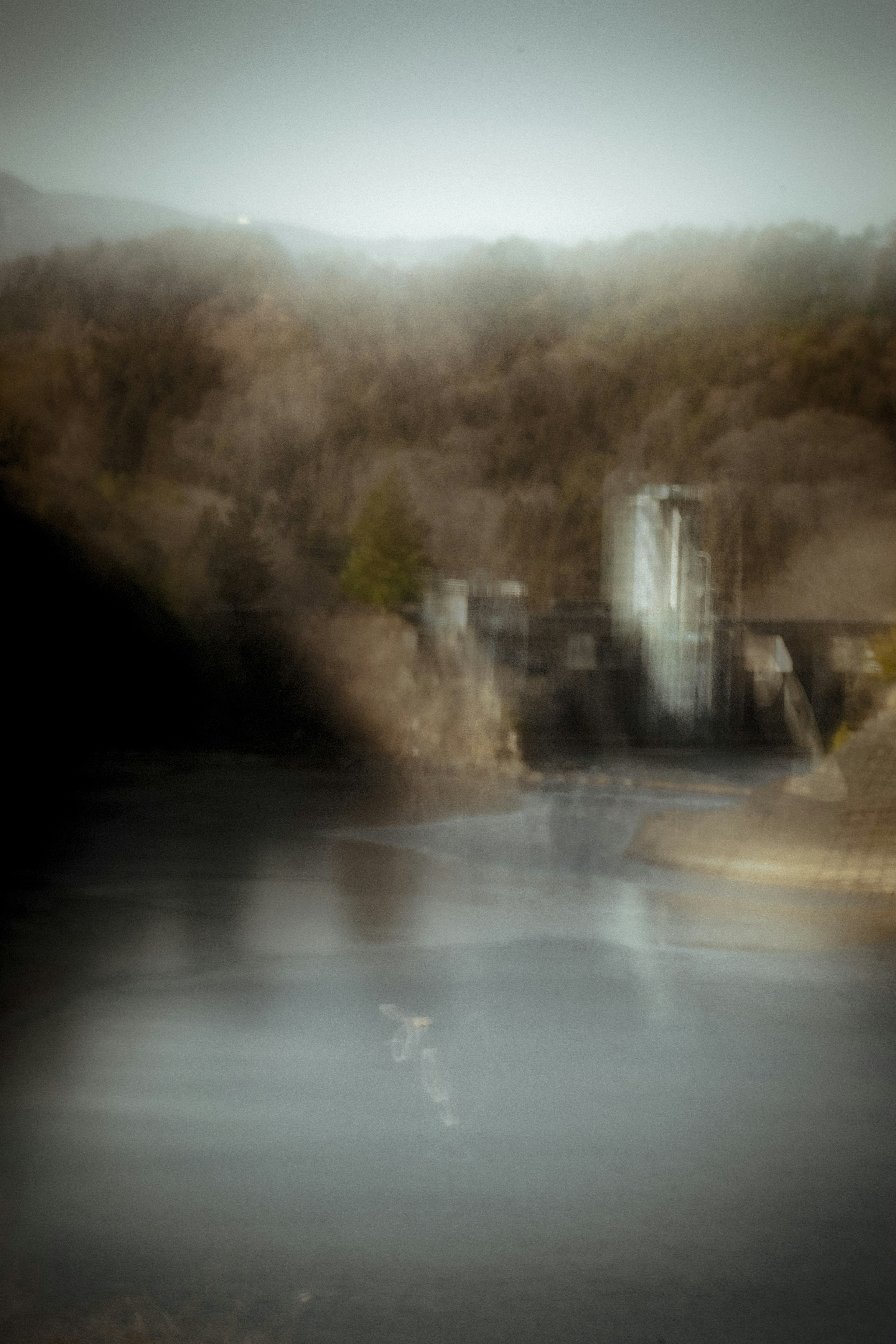 Verschwommene Landschaft mit einem Damm und ruhigem Wasser