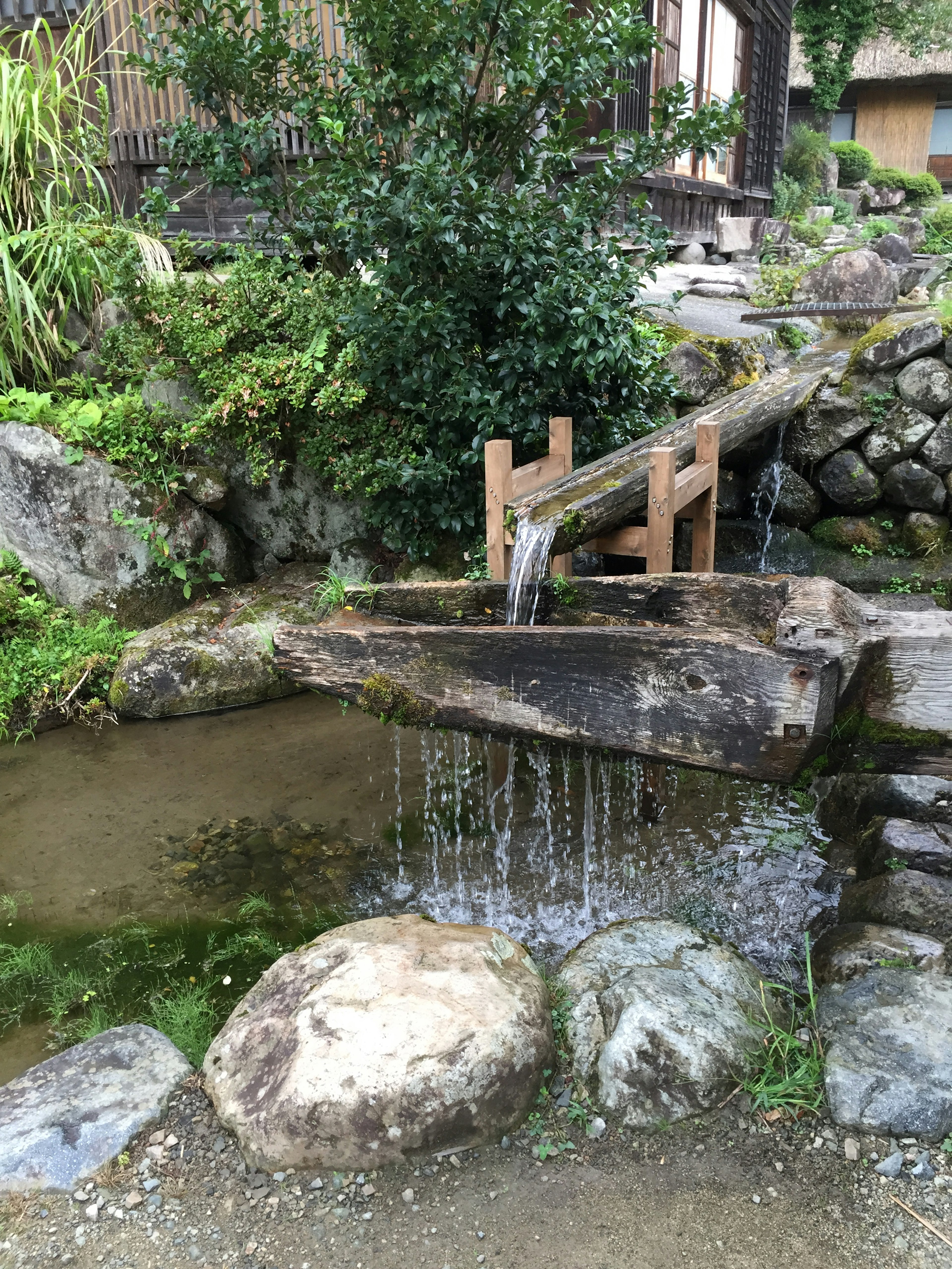 Scène de jardin japonais serein avec de l'eau qui coule des pierres et des structures en bois