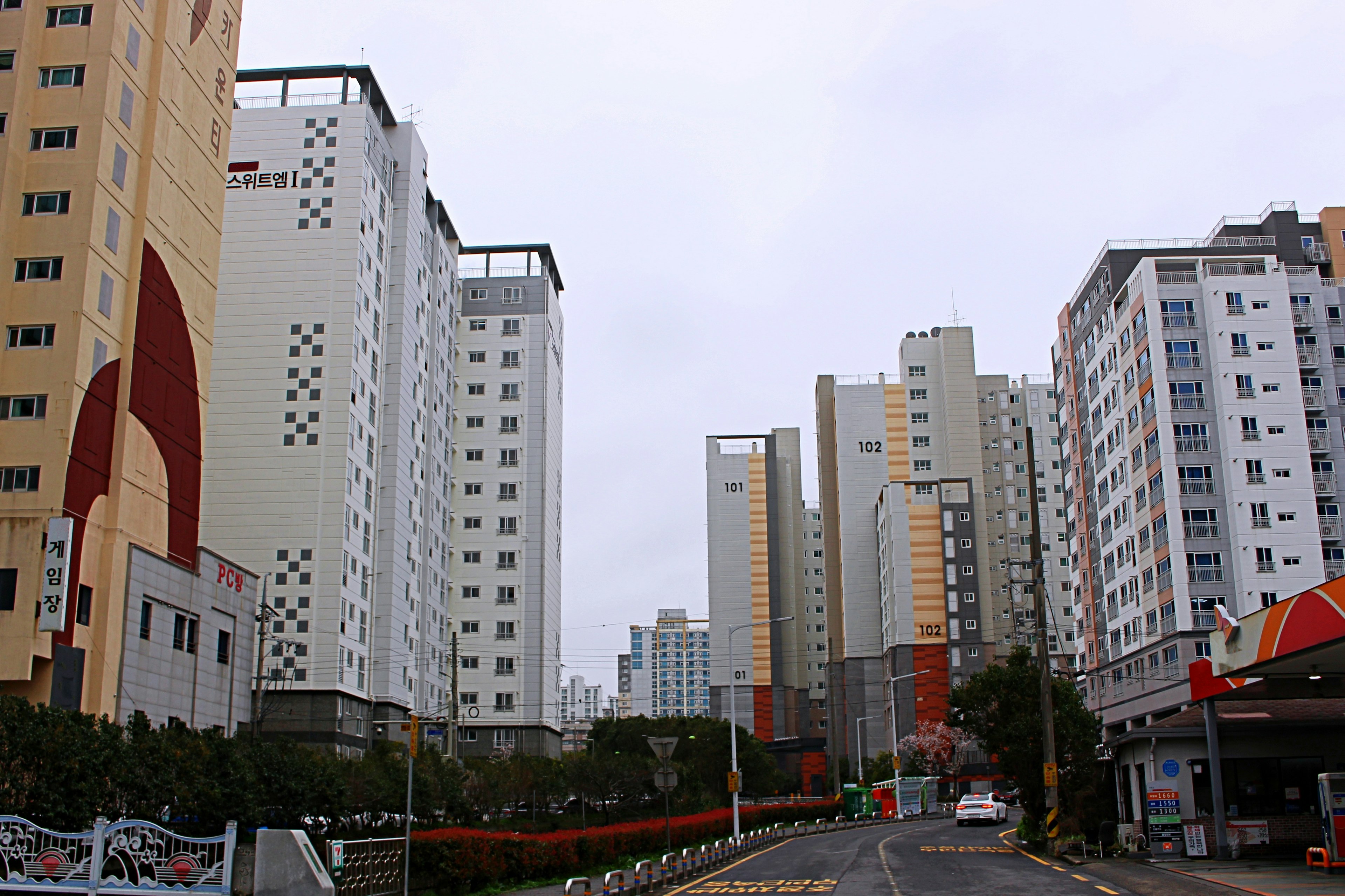 Paisaje urbano con edificios altos bajo un cielo nublado y una carretera visible