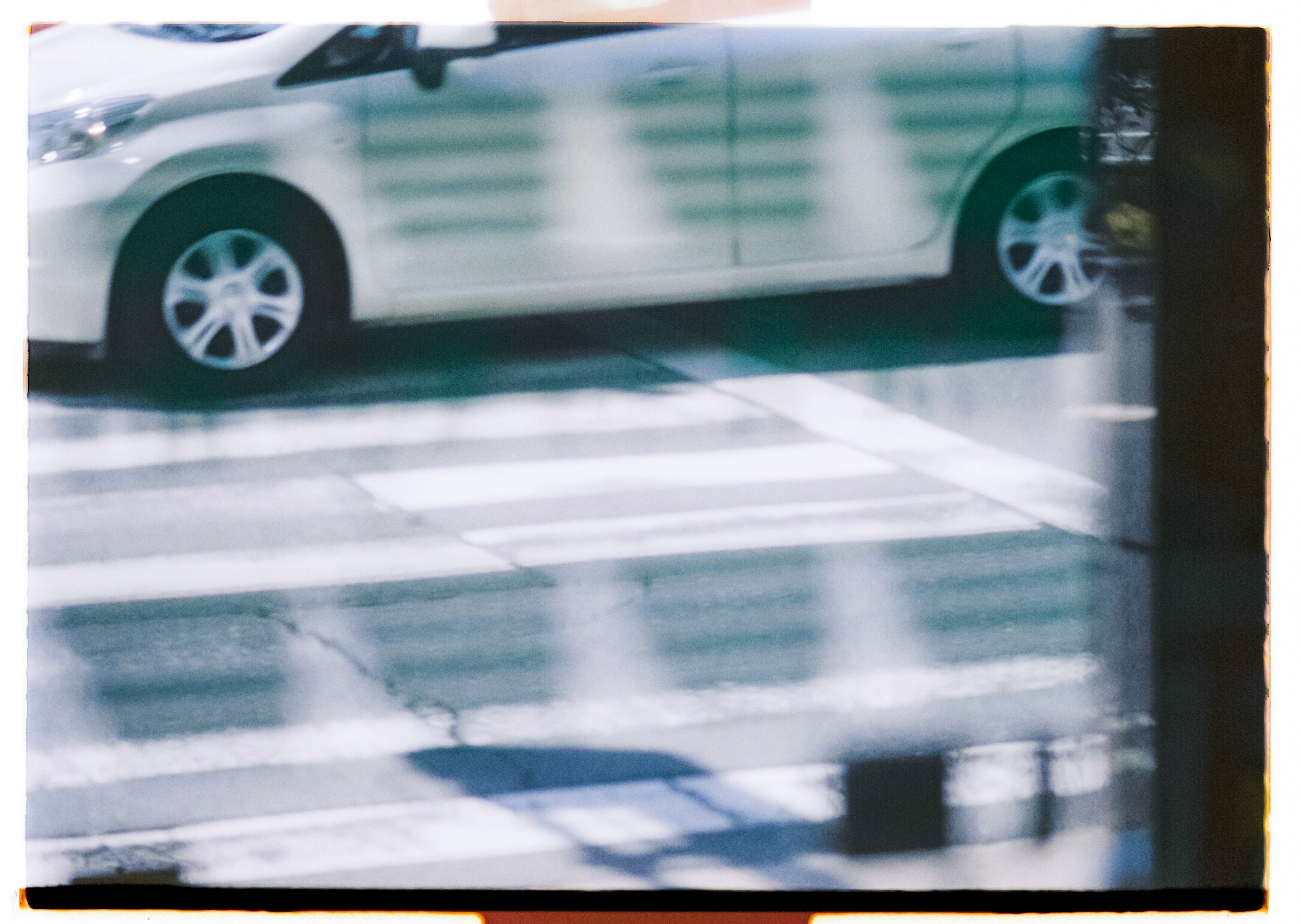 A white car near a crosswalk in an urban setting