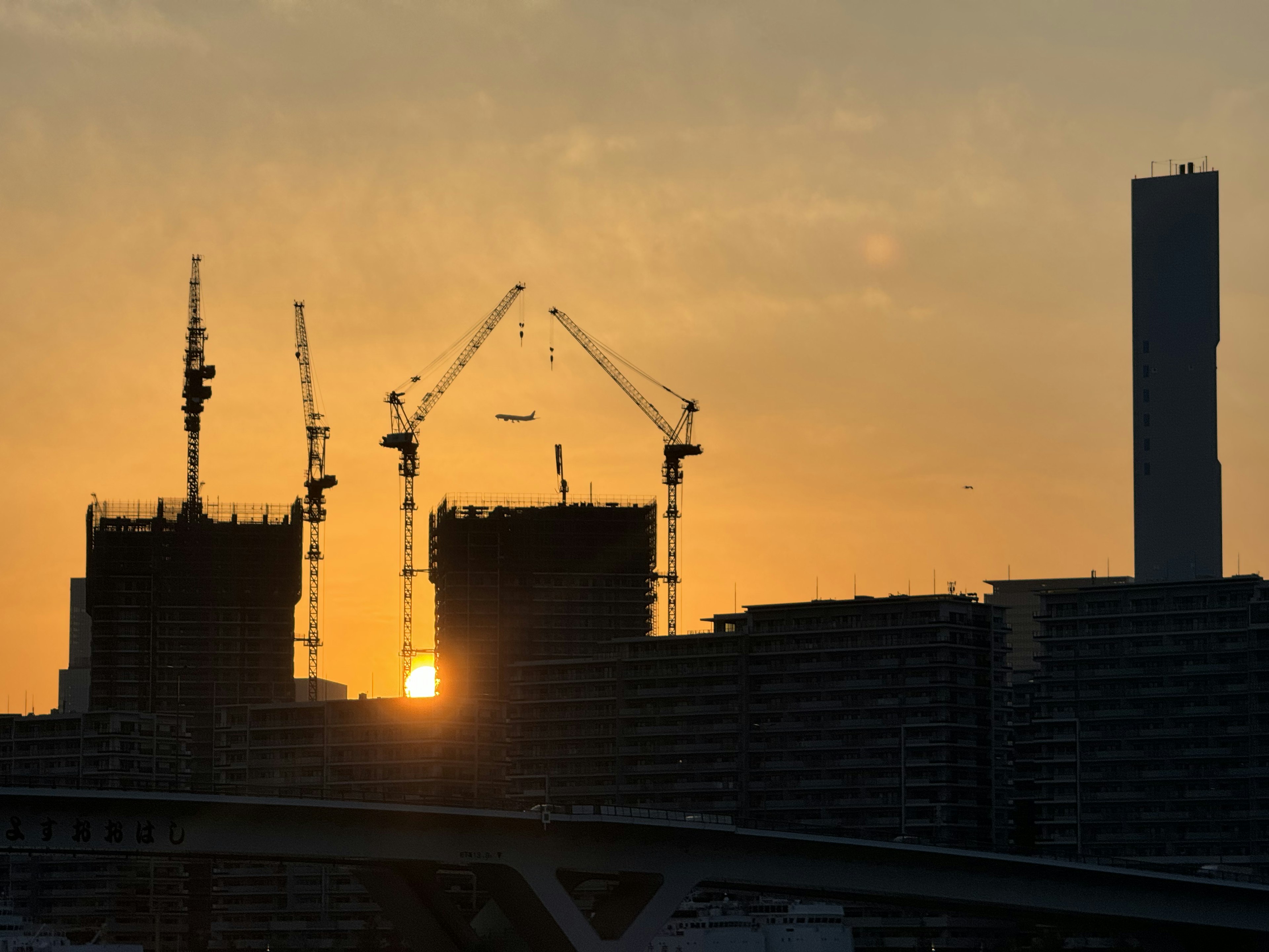 Silhouette di gru da costruzione e edifici contro un cielo al tramonto