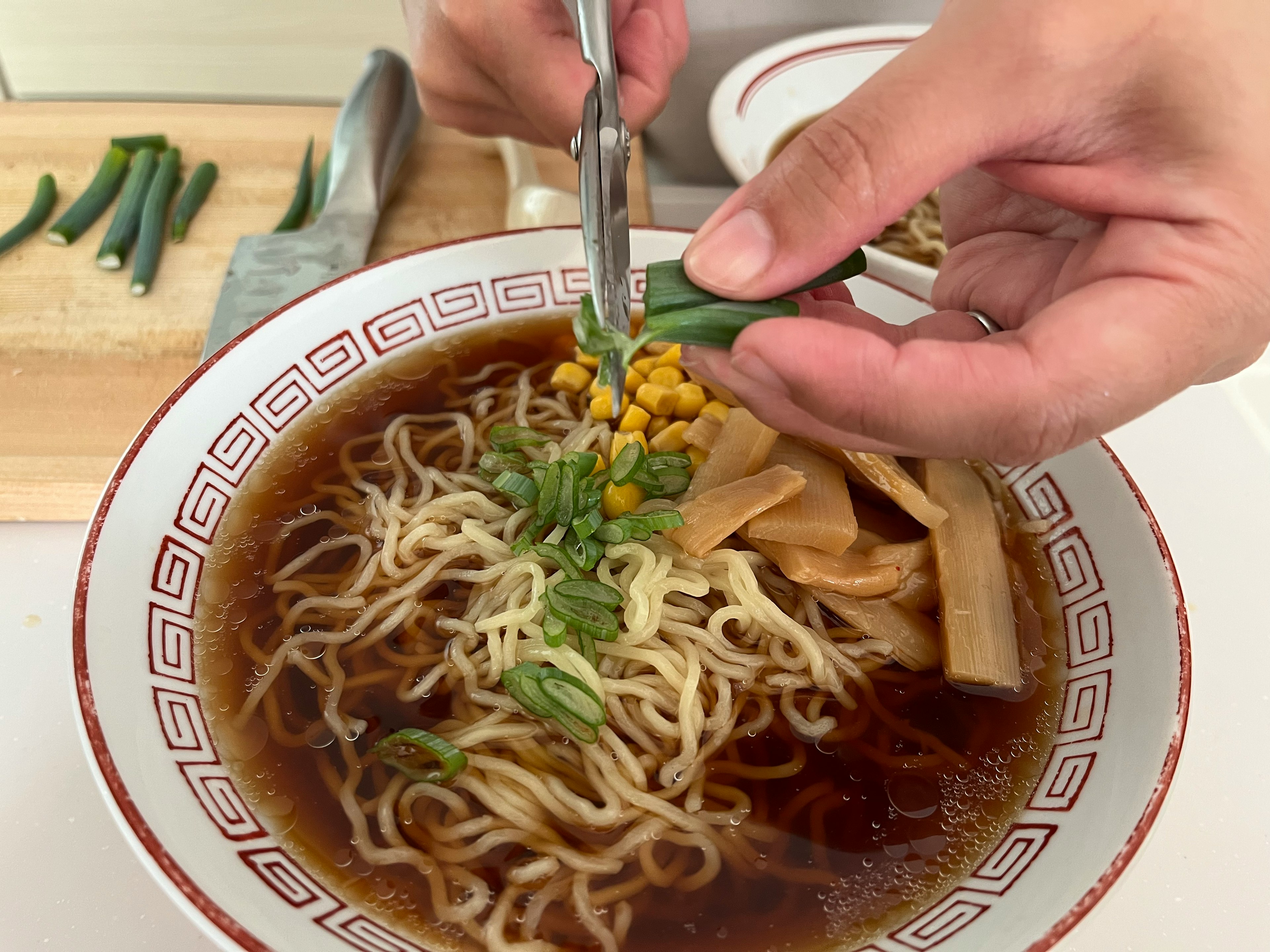 Tay đang thêm topping vào bát ramen