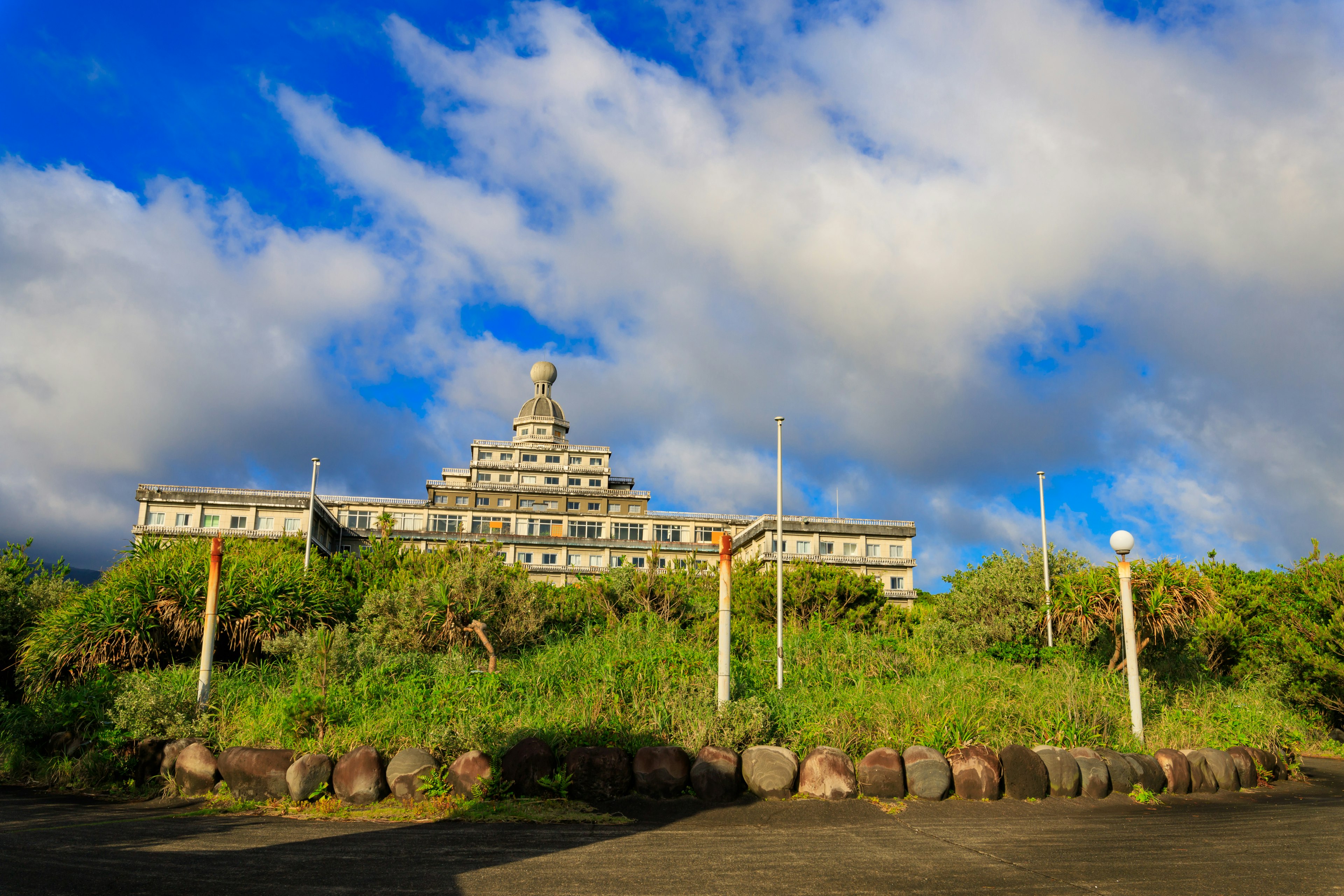 緑に囲まれた建物の上にそびえる像と青空の風景