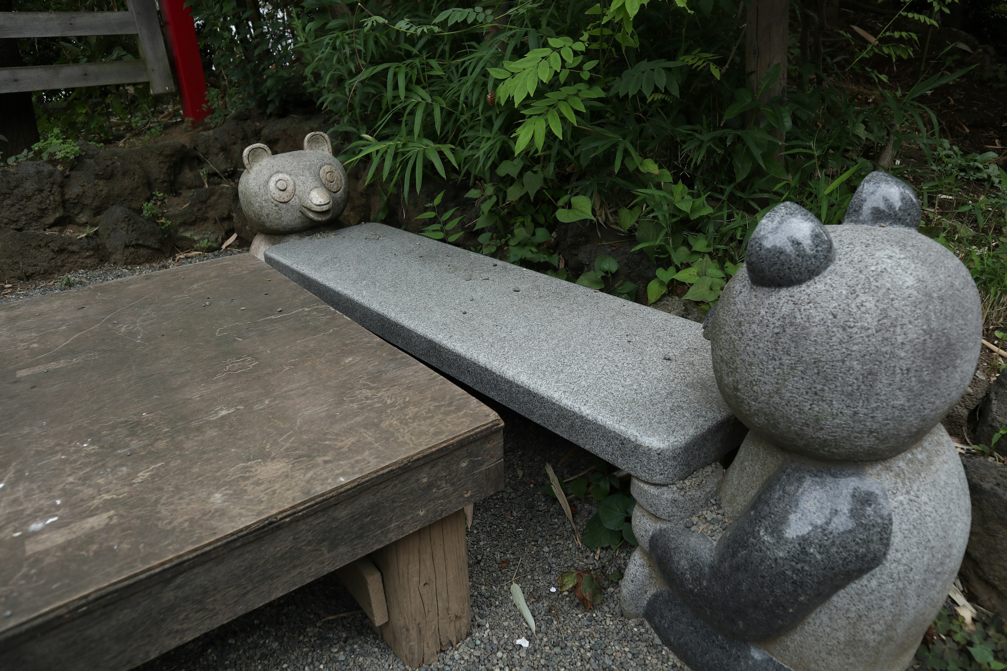 Esculturas de pandas de piedra como banco y mesa en un parque con vegetación exuberante