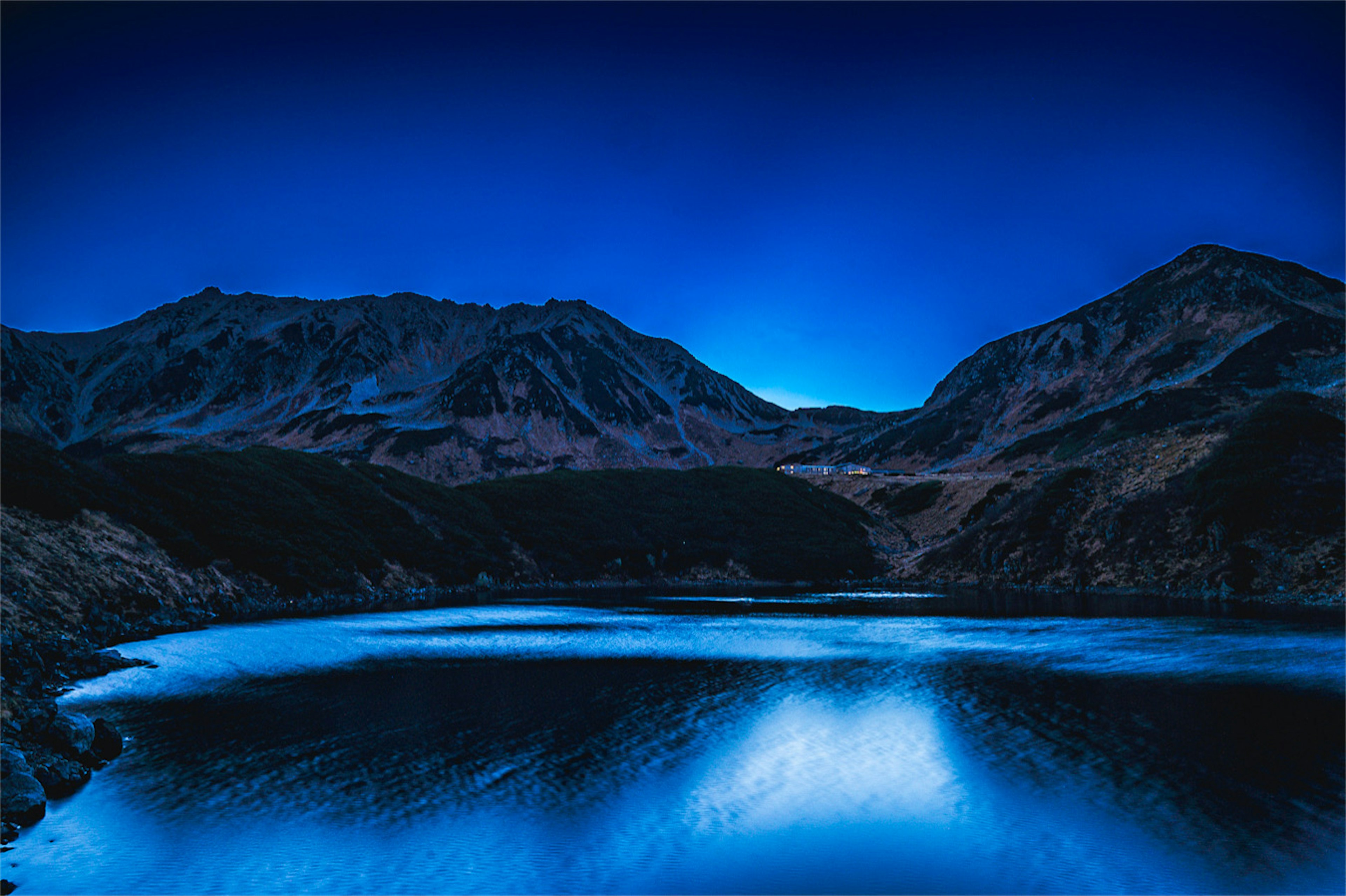 Lago blu circondato da montagne sotto un cielo crepuscolare