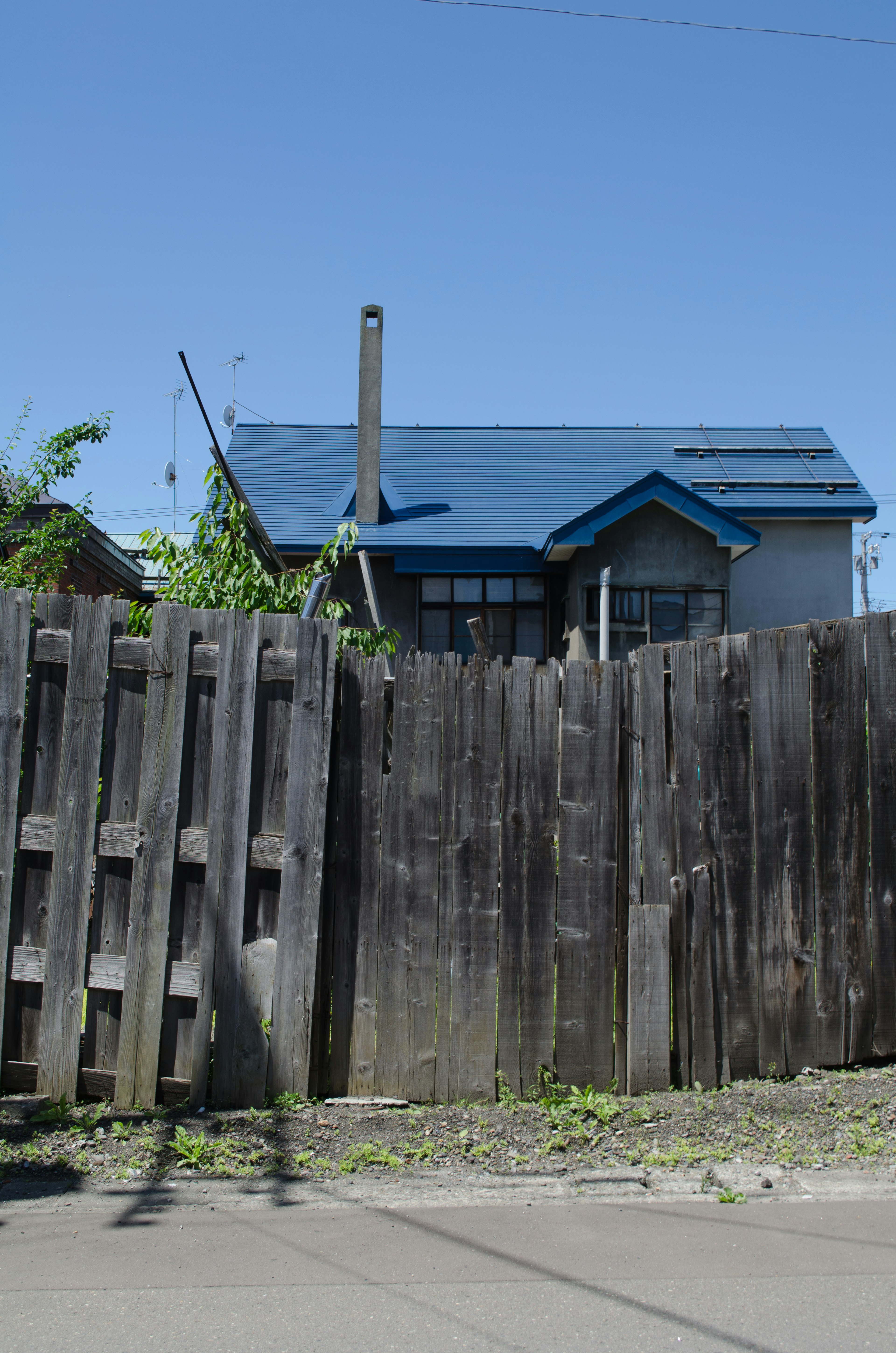 Une maison avec un toit bleu derrière une clôture en bois