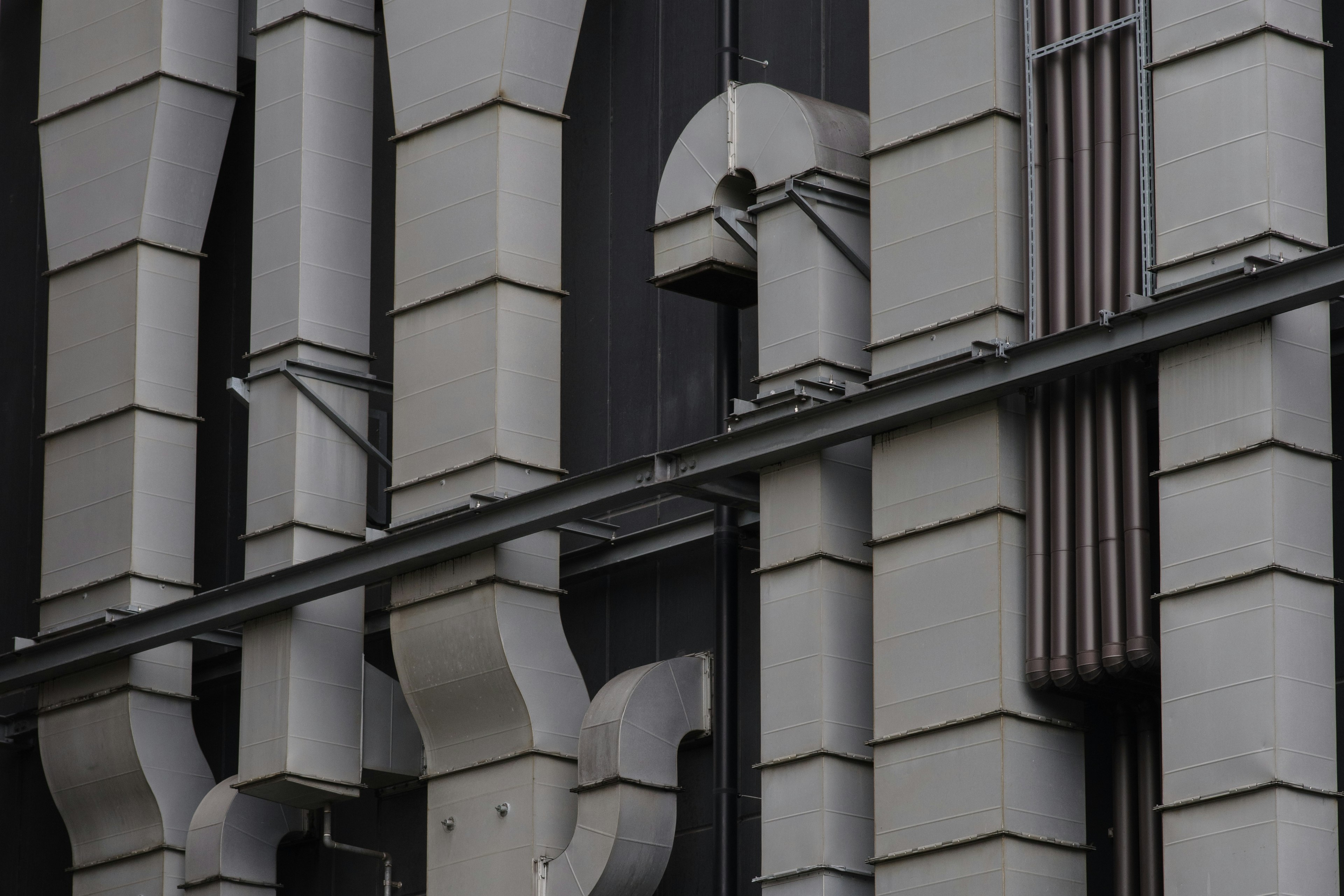 Tuberías y estructuras decorativas en una fachada de edificio gris