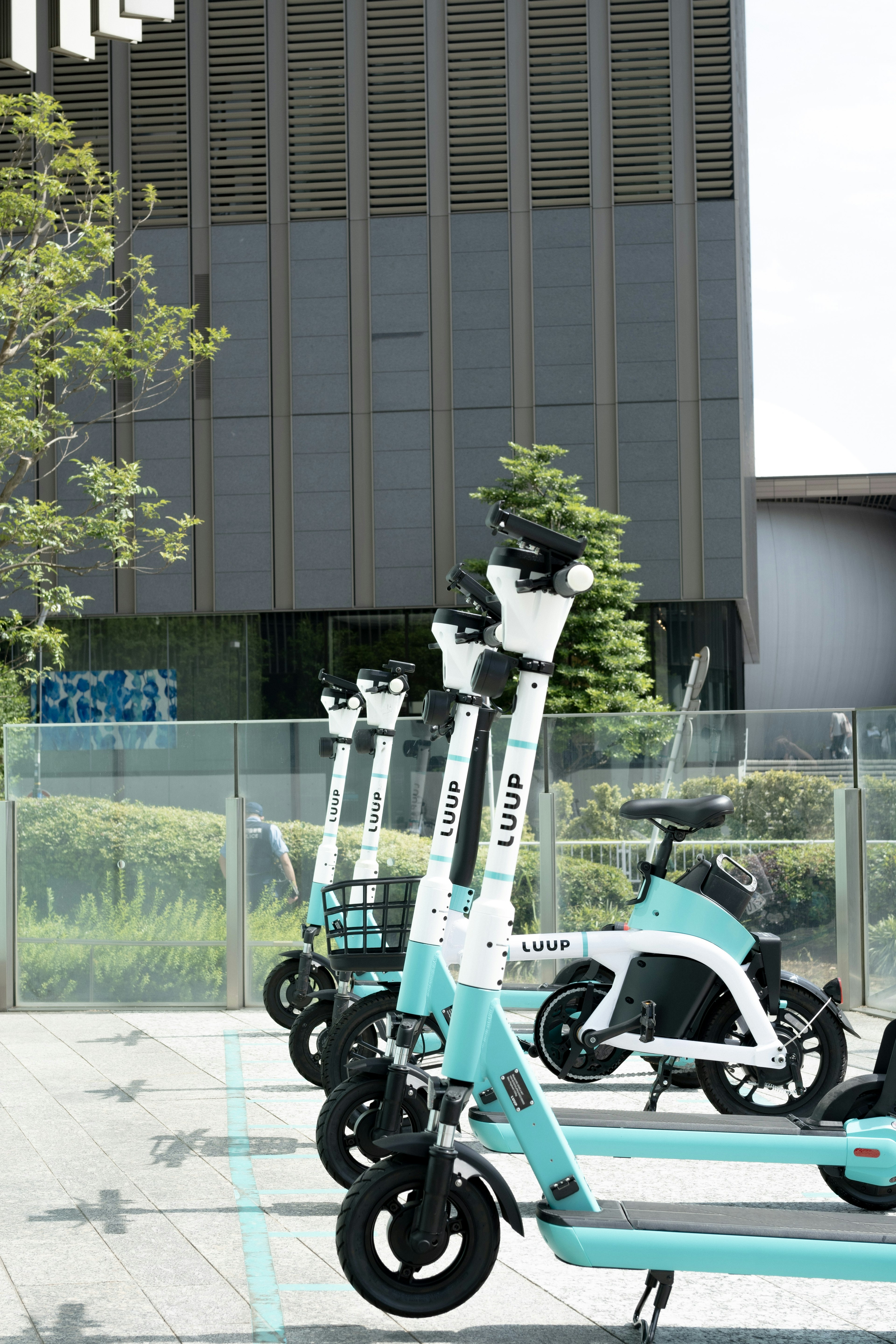 Row of blue and white electric scooters in a parking area modern building in the background